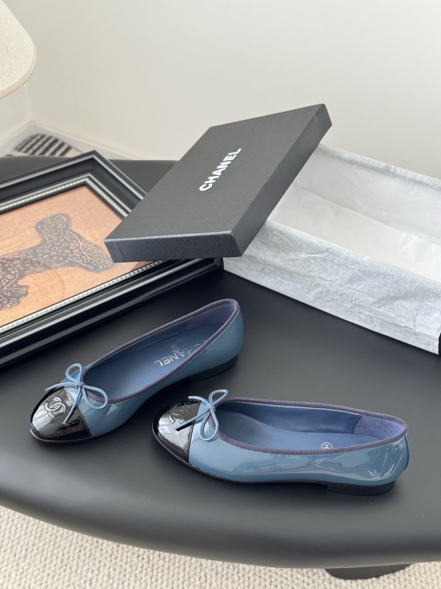 A pair of Chanel two-tone patent leather ballet flats in blue and black with a bow detail and CC logo, displayed with the original Chanel box. - Hình 2