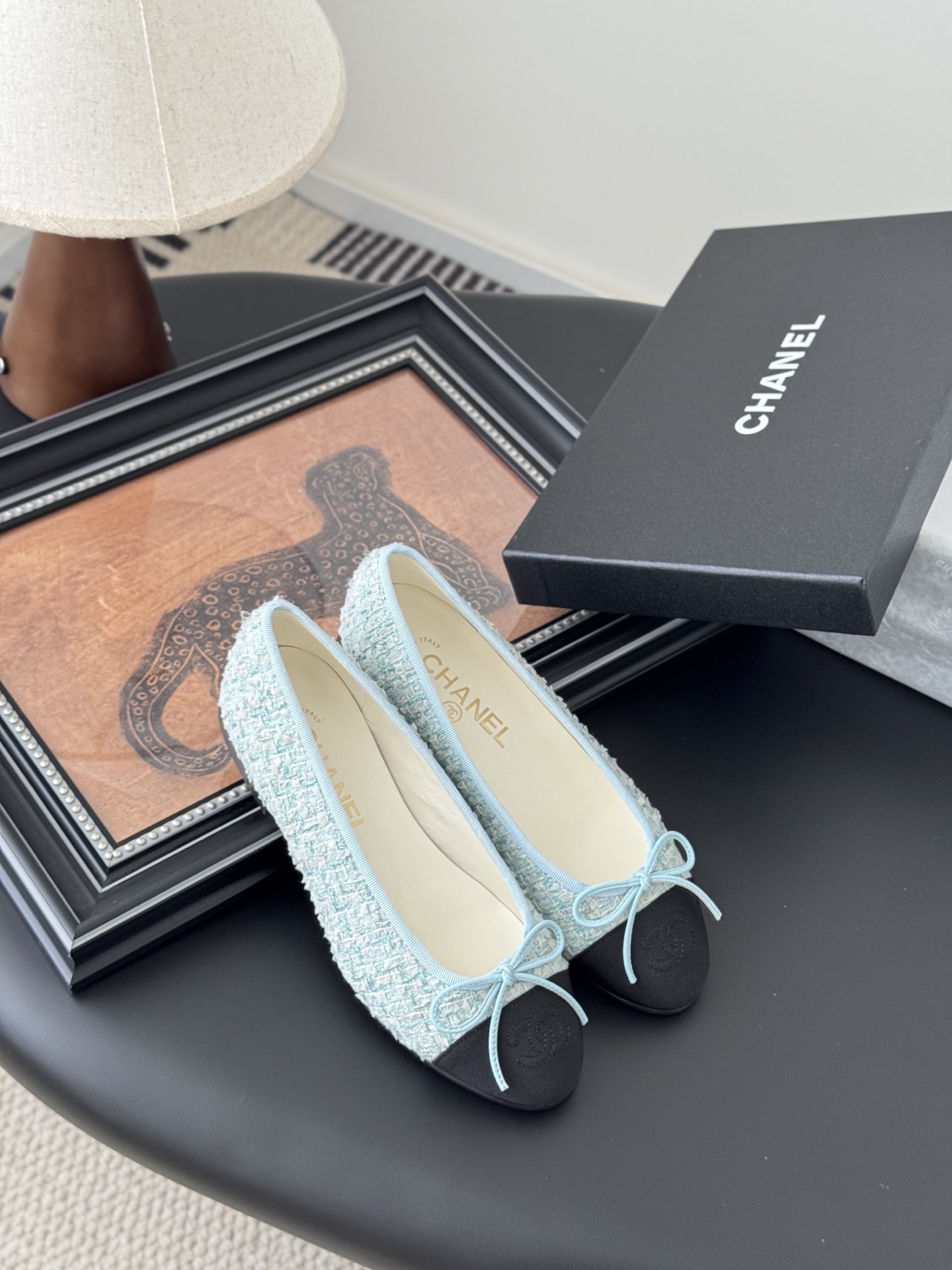 A pair of Chanel light blue tweed ballerina flats with black cap toe and bow detail next to a Chanel luxury box. - Hình 7