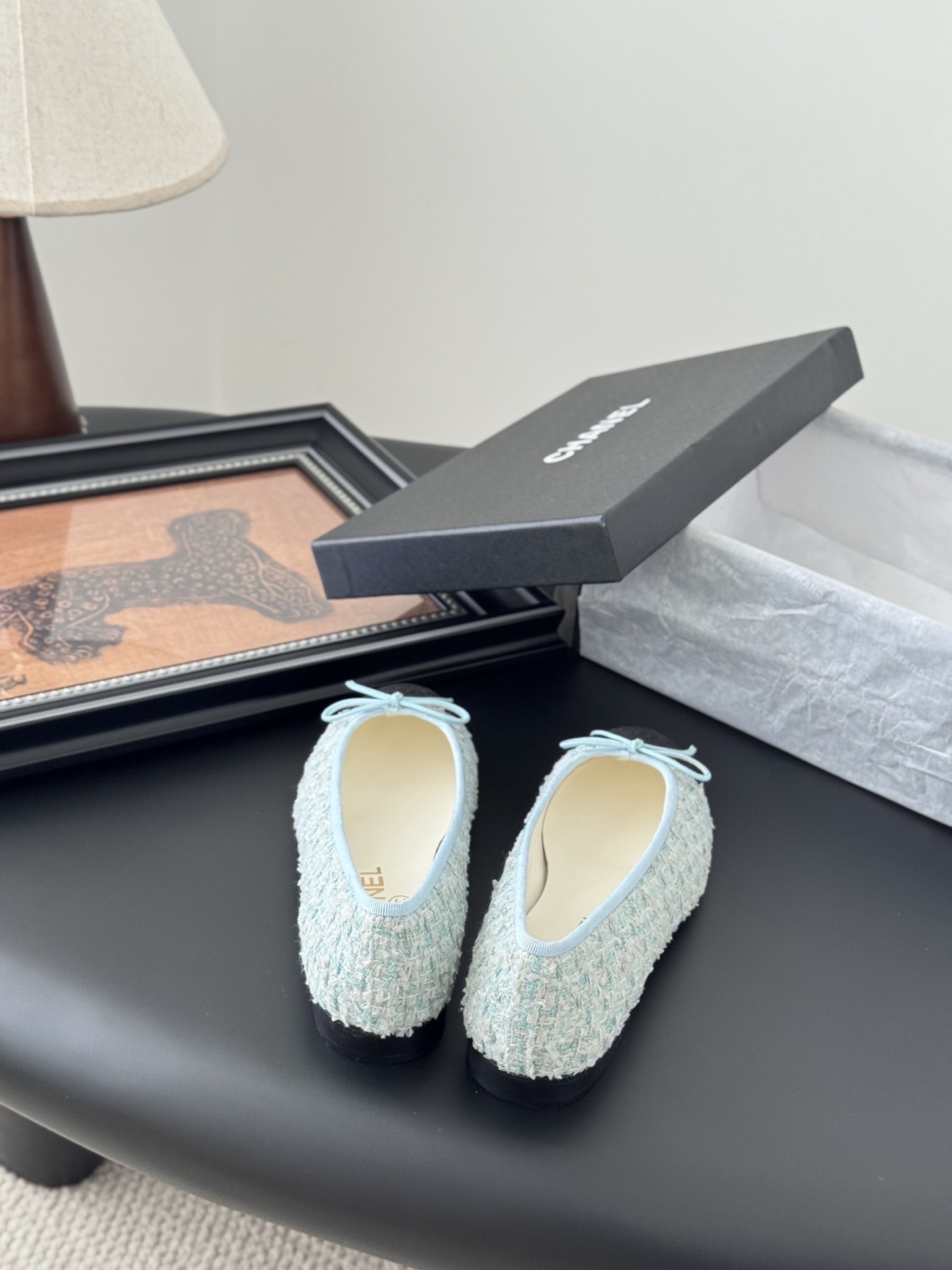 A pair of Chanel light blue tweed ballerina flats with black cap toe and bow detail next to a Chanel luxury box. - Hình 6