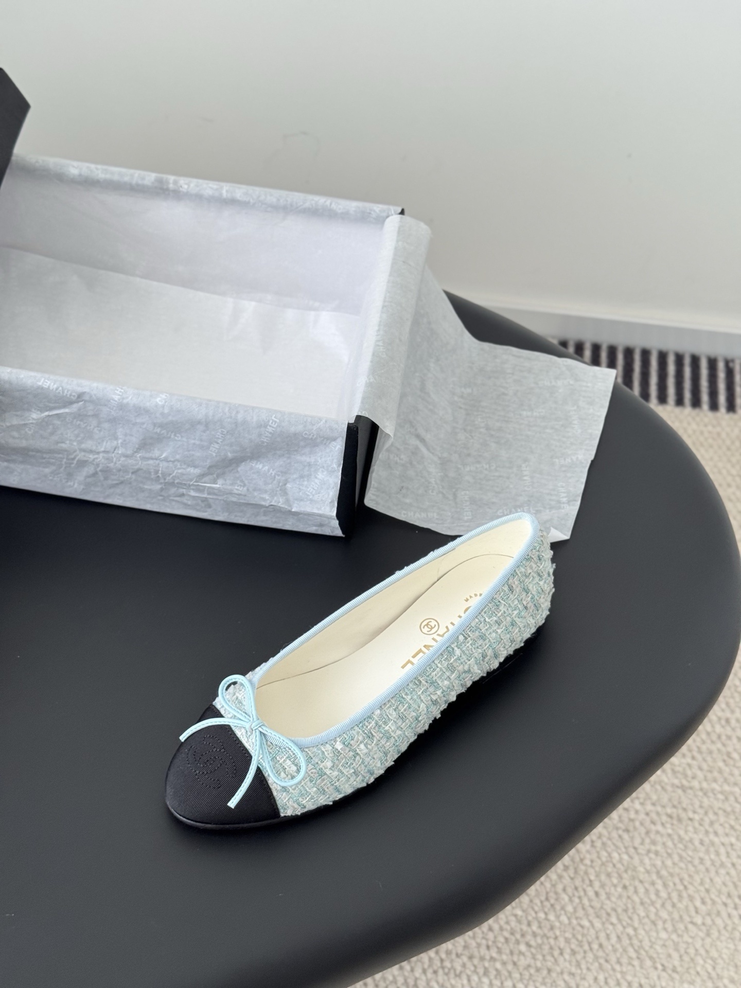 A pair of Chanel light blue tweed ballerina flats with black cap toe and bow detail next to a Chanel luxury box. - Hình 5
