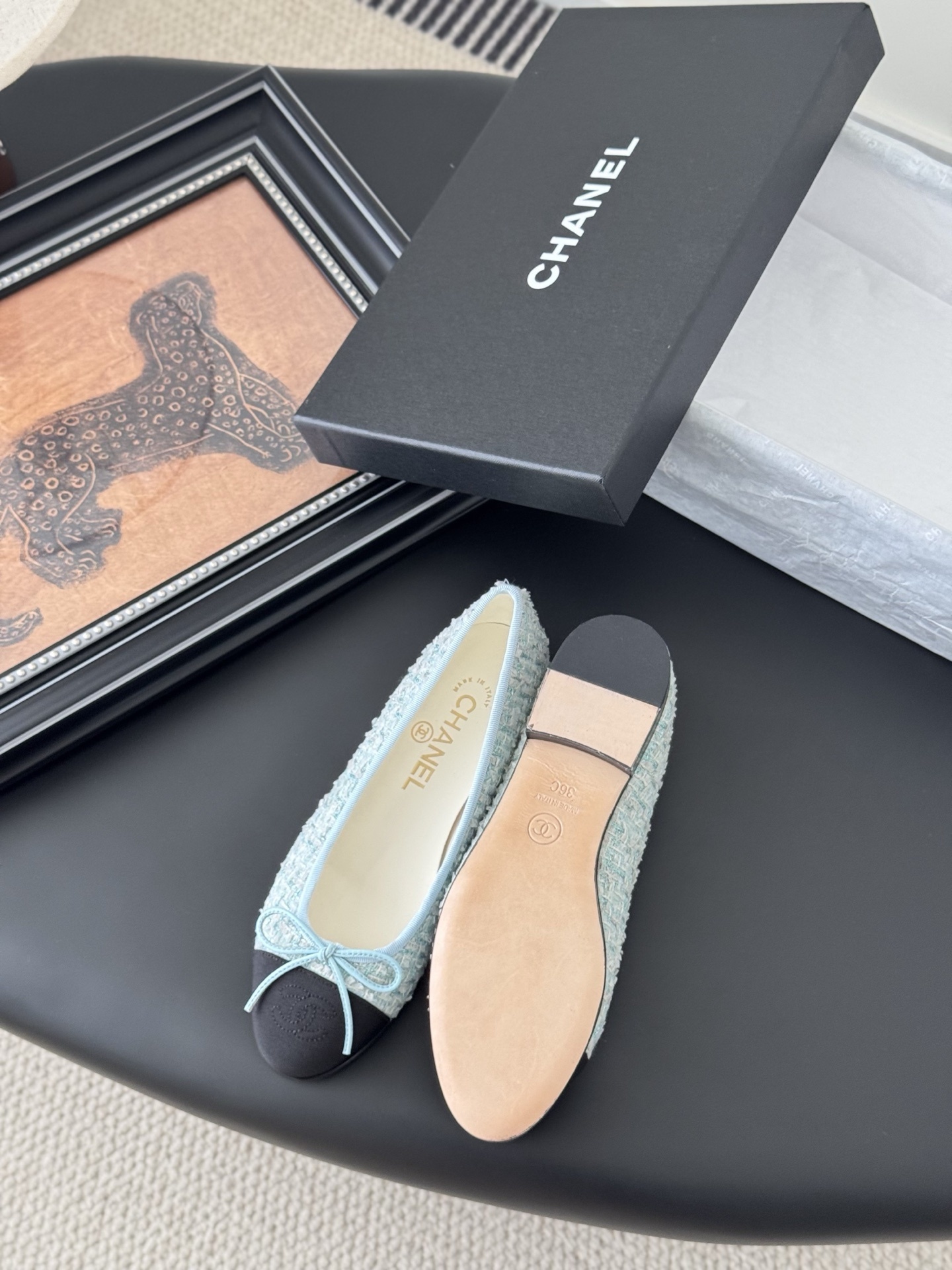 A pair of Chanel light blue tweed ballerina flats with black cap toe and bow detail next to a Chanel luxury box. - Hình 4