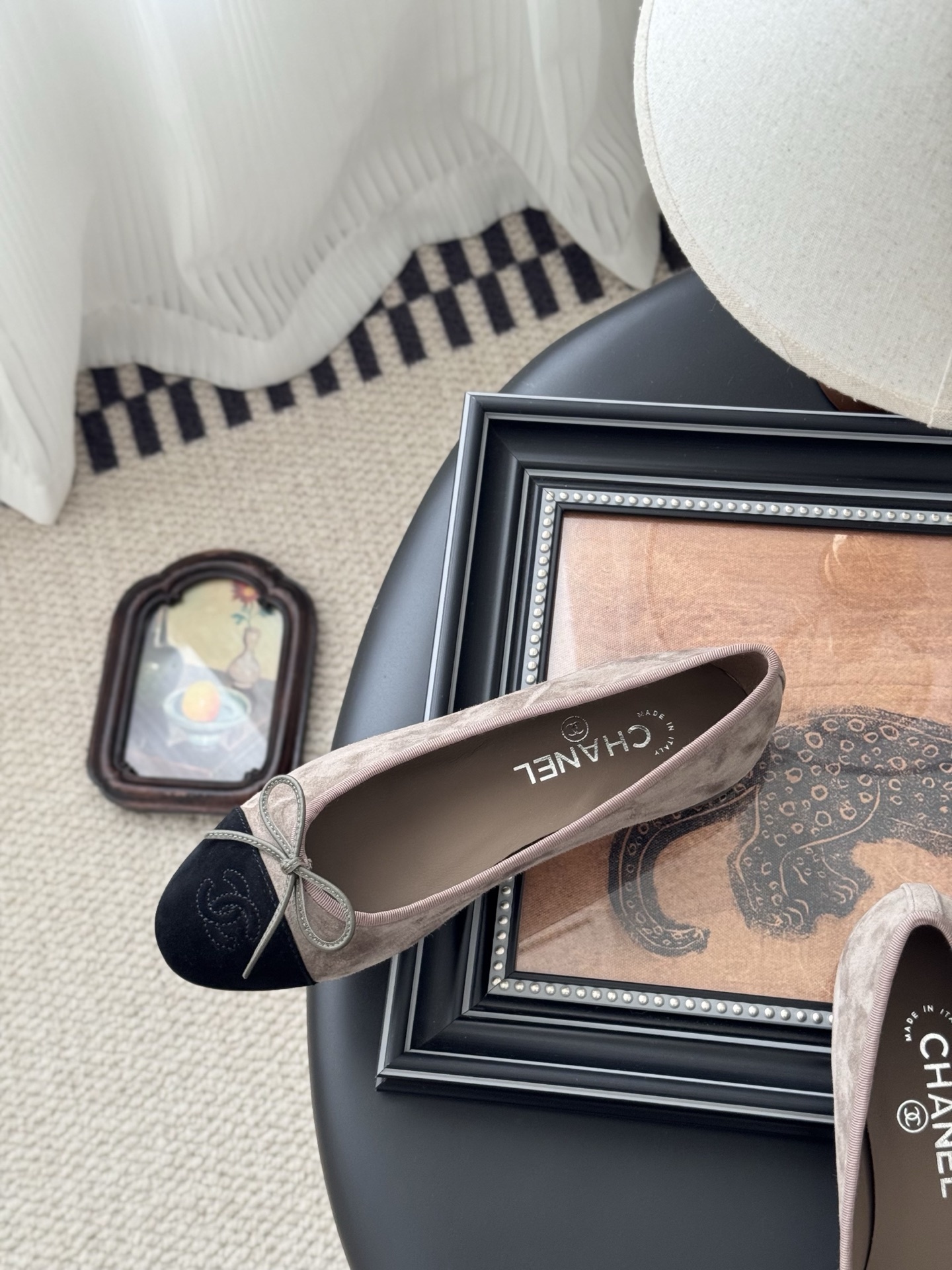 Luxury Chanel beige suede ballerina flats with black CC logo toe cap placed next to a black Chanel shoe box on a dark table. - Hình 8