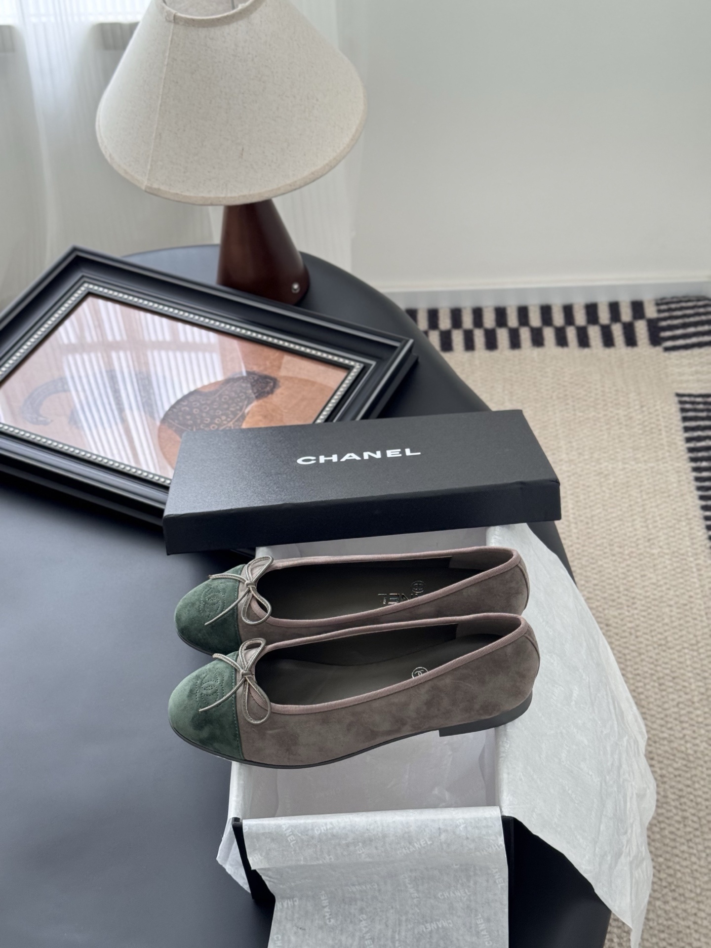 A pair of Chanel taupe suede ballerina flats with green suede cap toes and bow detail, presented next to a black Chanel shoe box. - Hình 9