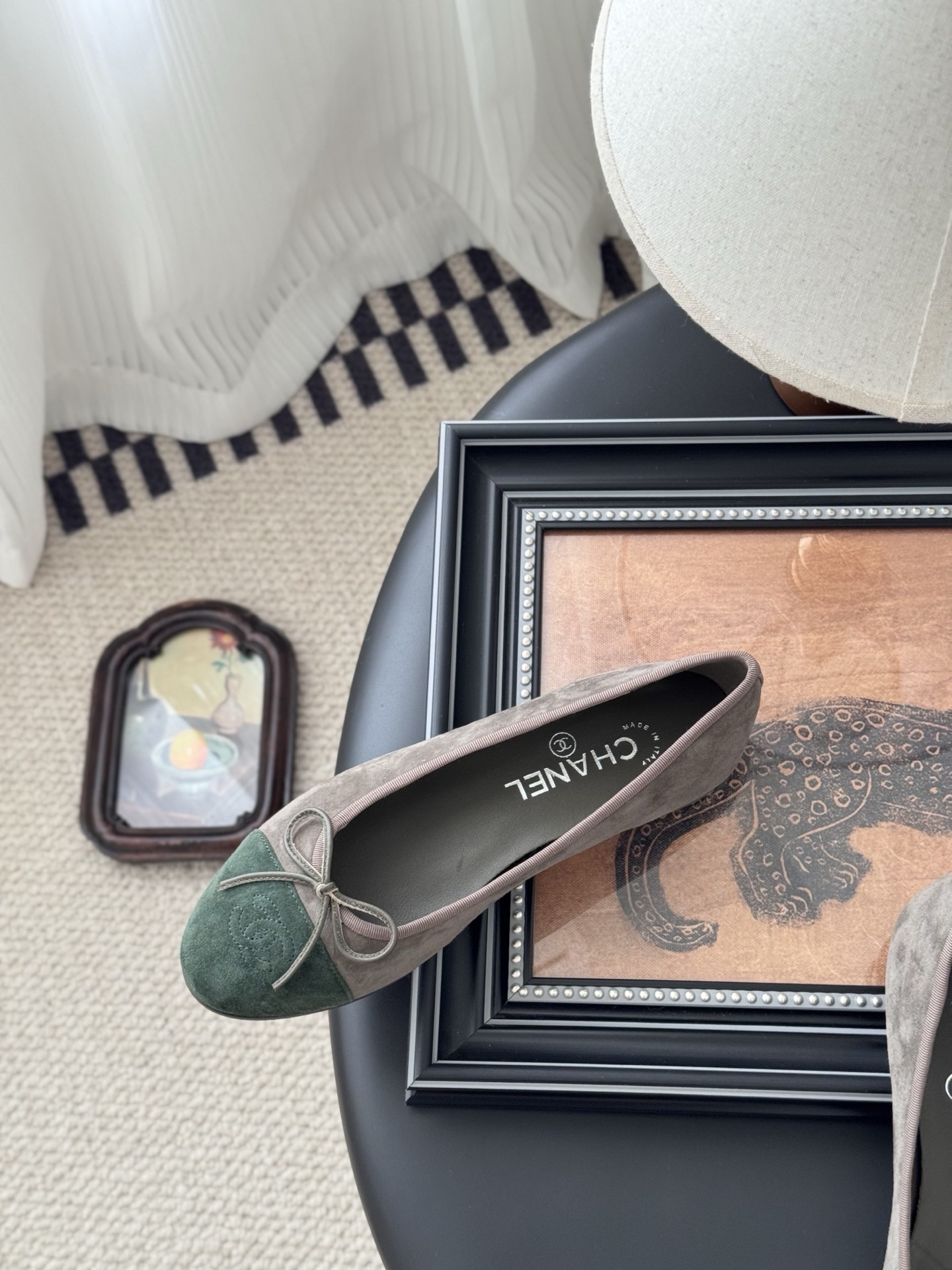 A pair of Chanel taupe suede ballerina flats with green suede cap toes and bow detail, presented next to a black Chanel shoe box. - Hình 8