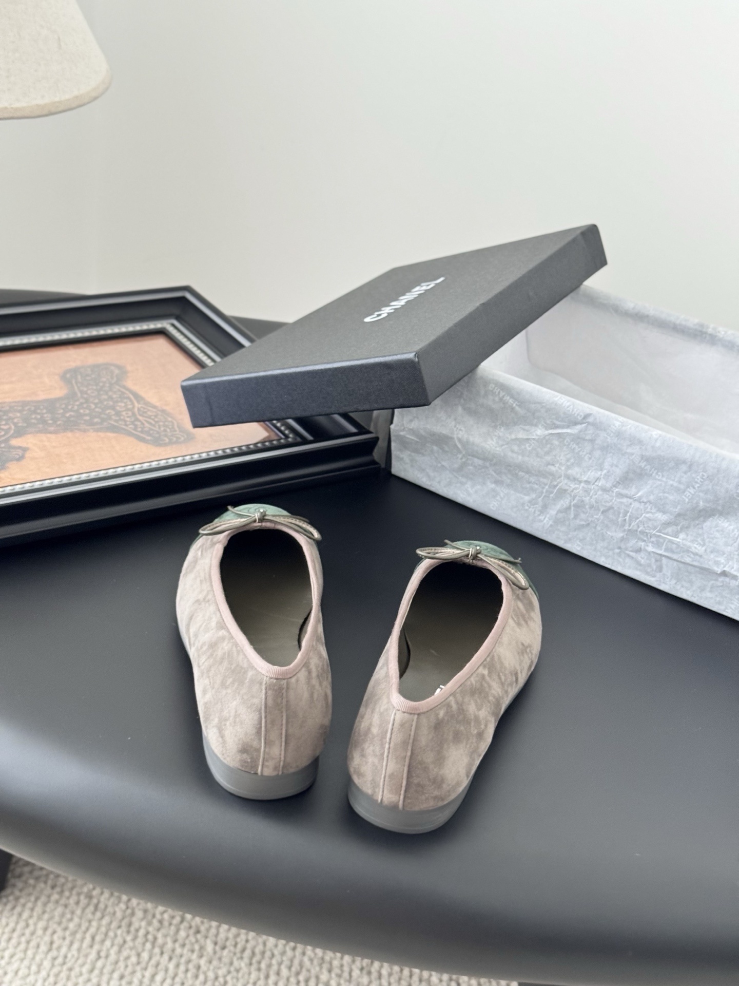A pair of Chanel taupe suede ballerina flats with green suede cap toes and bow detail, presented next to a black Chanel shoe box. - Hình 6