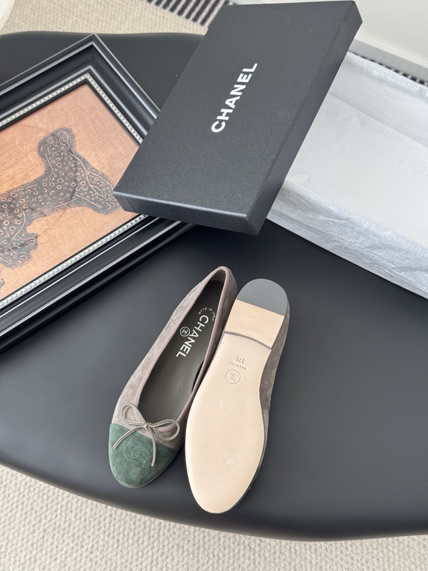 A pair of Chanel taupe suede ballerina flats with green suede cap toes and bow detail, presented next to a black Chanel shoe box. - Hình 4