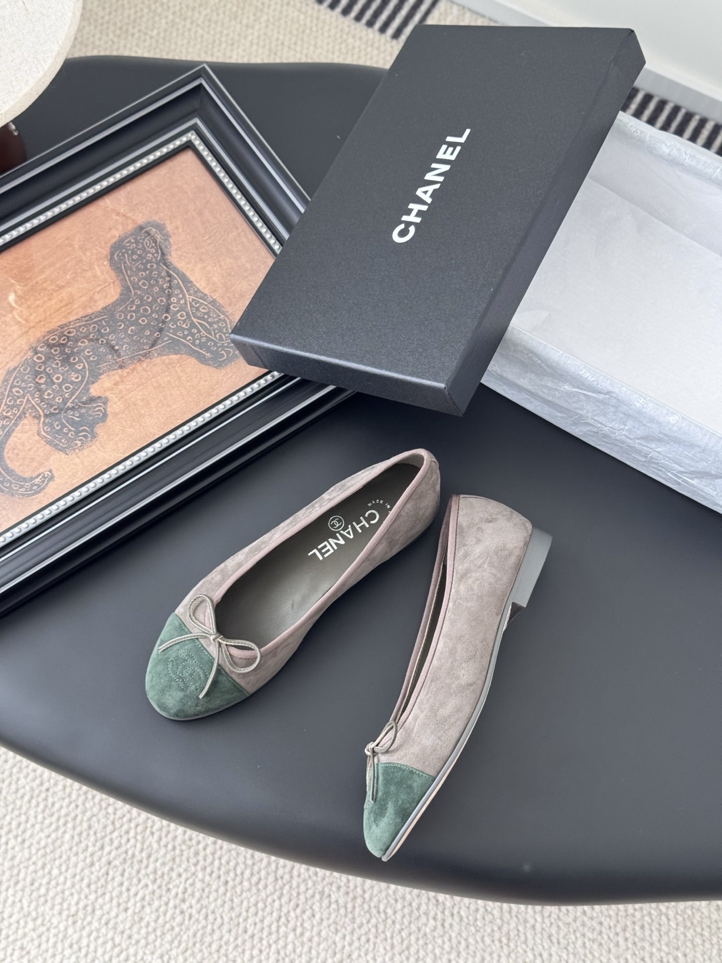 A pair of Chanel taupe suede ballerina flats with green suede cap toes and bow detail, presented next to a black Chanel shoe box. - Hình 3