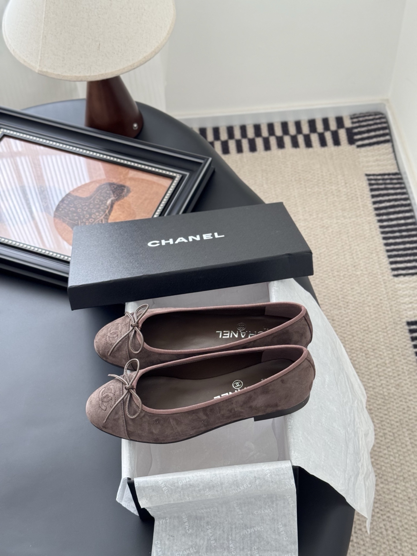 A pair of taupe Chanel suede ballet flats with embroidered CC logo and bow detail next to an original Chanel box - Hình 9