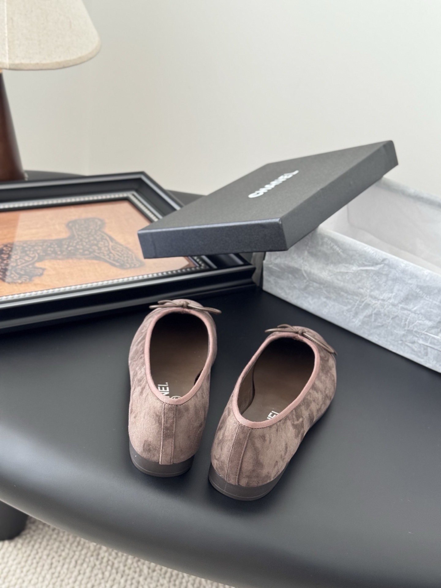 A pair of taupe Chanel suede ballet flats with embroidered CC logo and bow detail next to an original Chanel box - Hình 6