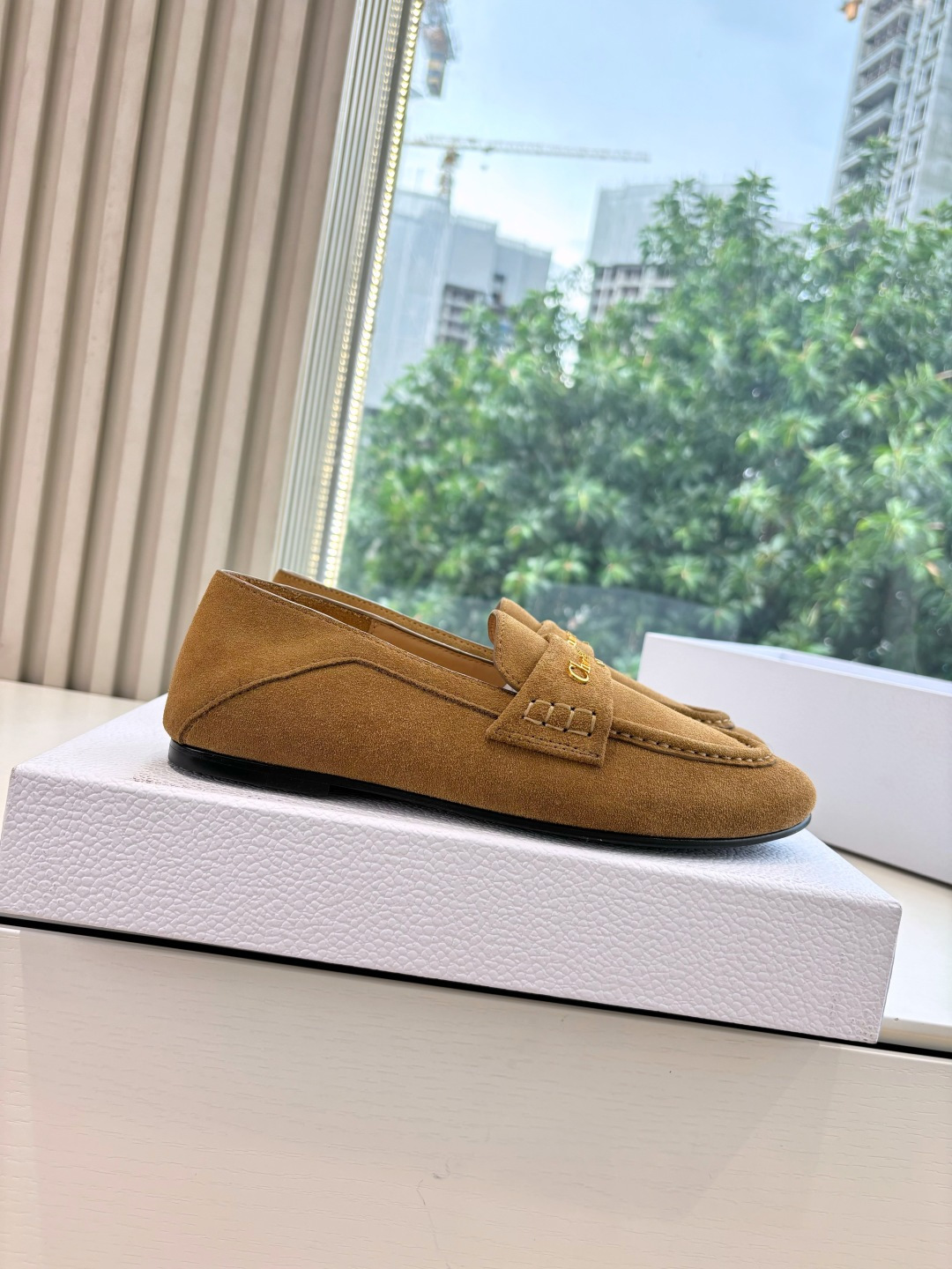 A pair of Christian Dior tan suede loafers with gold logo lettering displayed in a white Dior box. - Hình 7