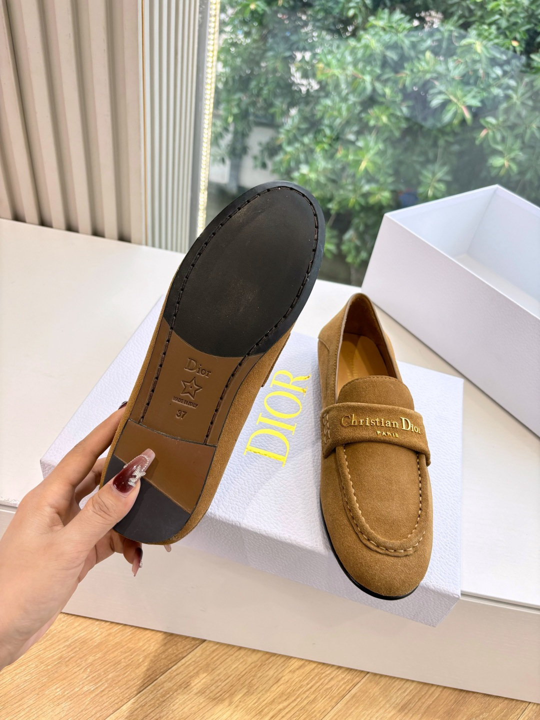 A pair of Christian Dior tan suede loafers with gold logo lettering displayed in a white Dior box. - Hình 6