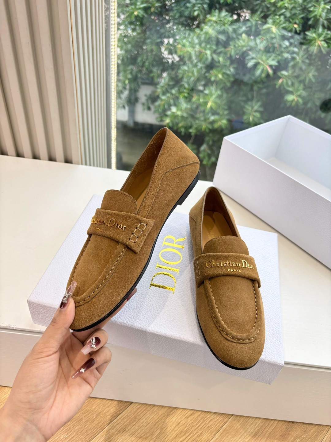 A pair of Christian Dior tan suede loafers with gold logo lettering displayed in a white Dior box. - Hình 5