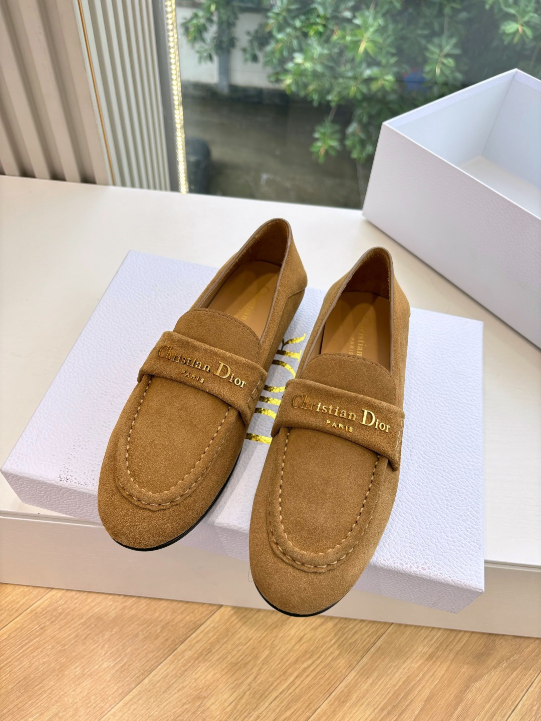 A pair of Christian Dior tan suede loafers with gold logo lettering displayed in a white Dior box. - Hình 4