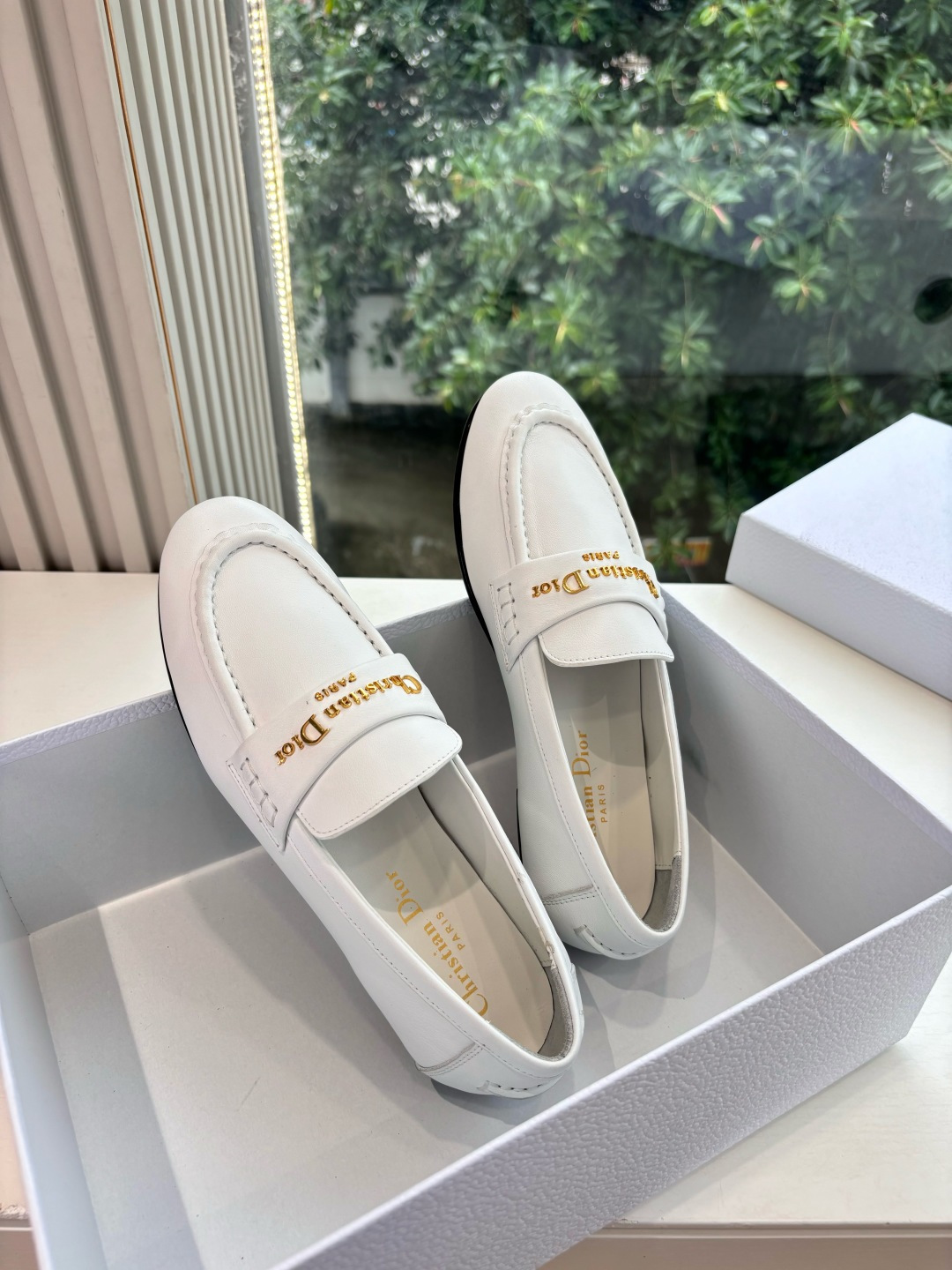 A pair of elegant white Christian Dior leather loafers with gold-tone signature logo in a luxury white gift box. - Hình 2