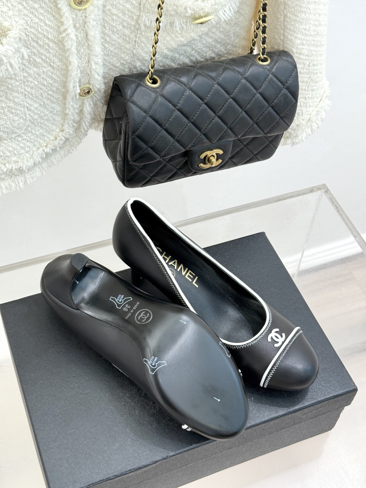 Elegant black Chanel leather pumps with white trim and CC logo resting on a black designer box - Hình 9