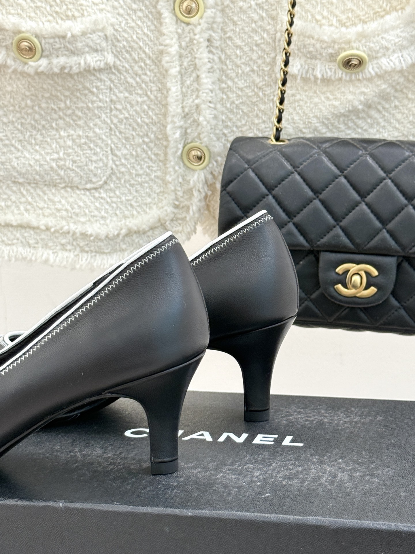 Elegant black Chanel leather pumps with white trim and CC logo resting on a black designer box - Hình 6