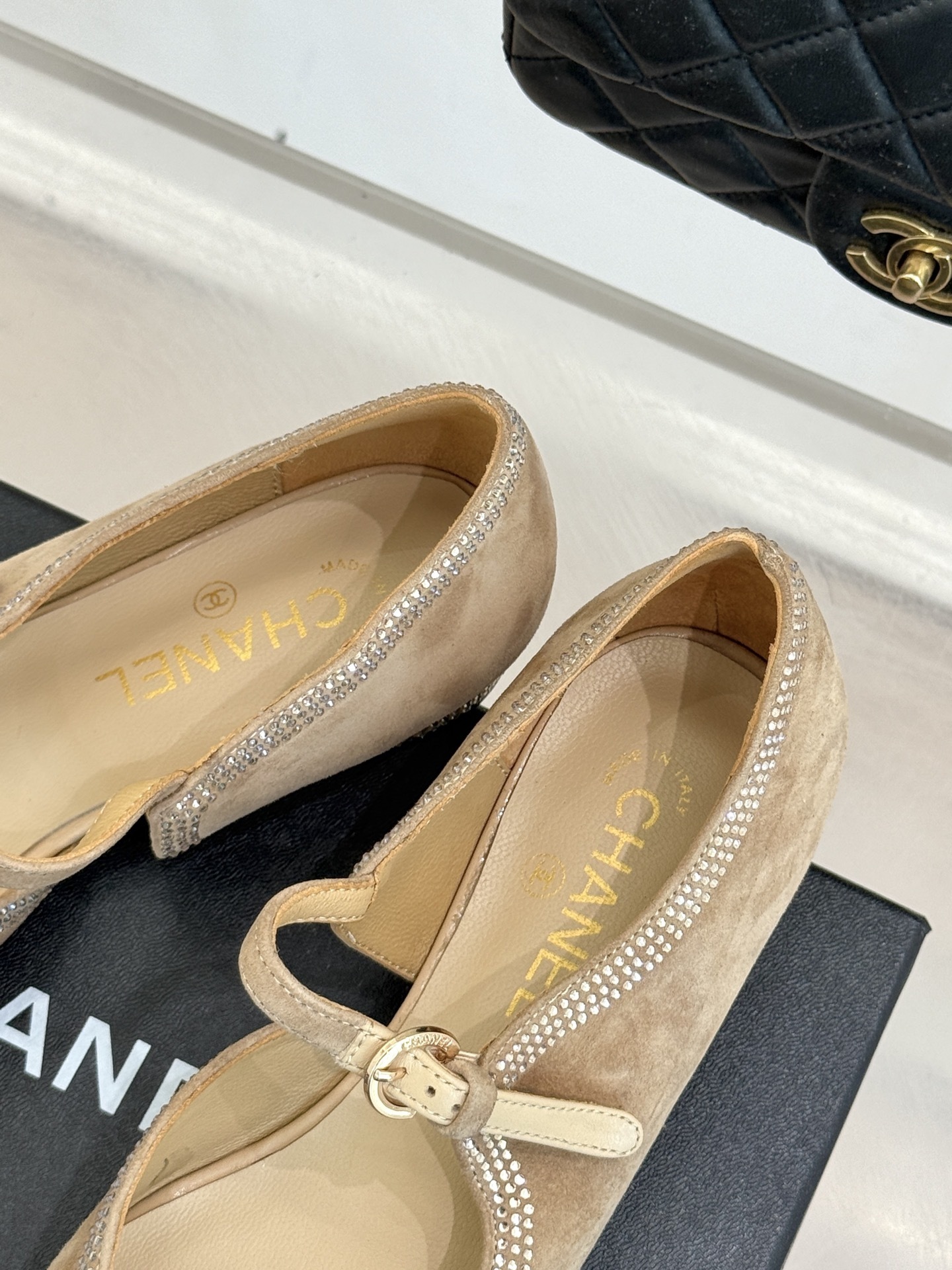 Chanel beige suede Mary Jane flats with black pointed cap-toes and crystal rhinestone trim displayed on a black box. - Hình 8