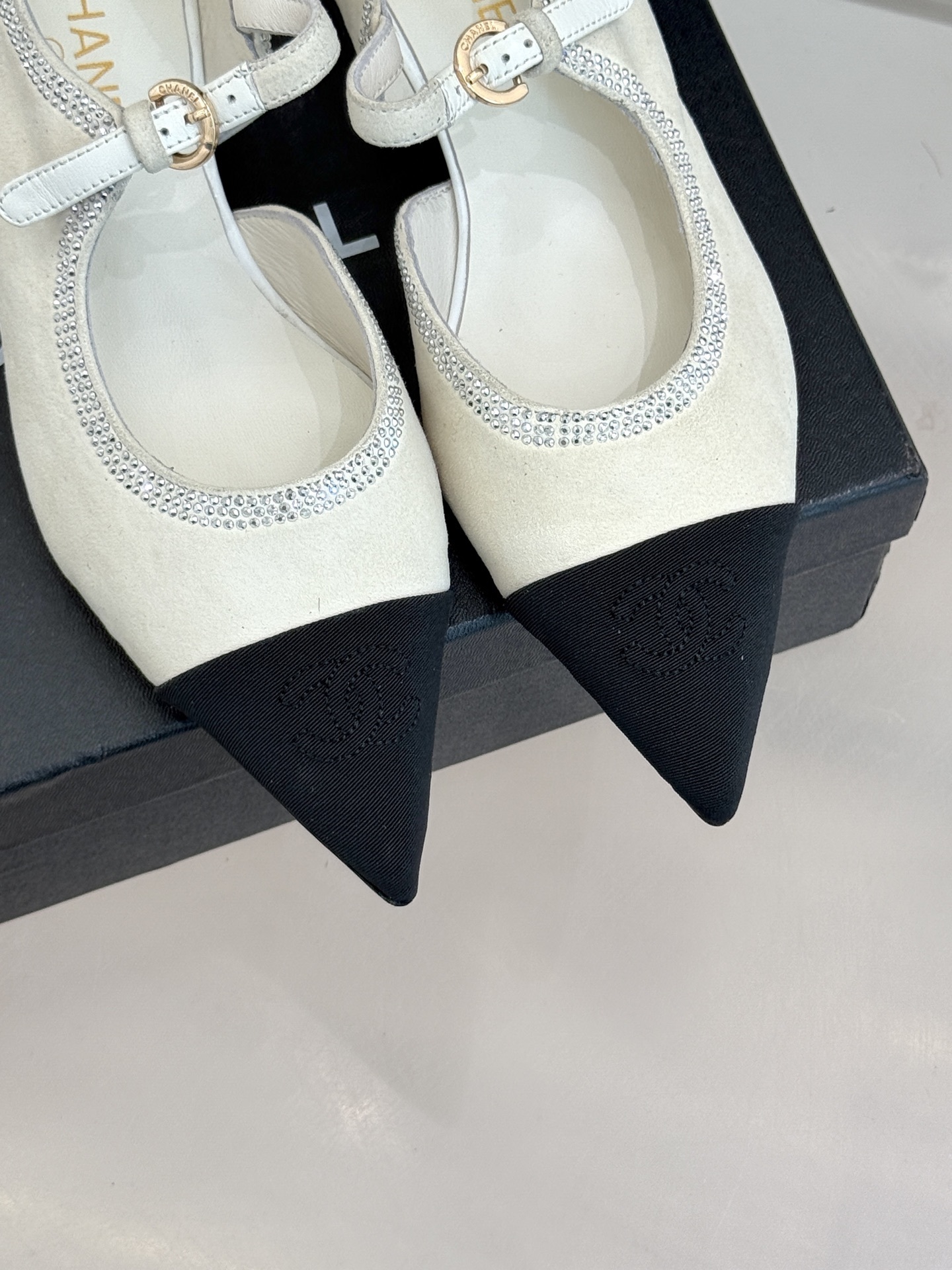 Luxury Chanel white suede Mary Jane flats with crystal trim and black cap toe displayed on a black designer box. - Hình 7
