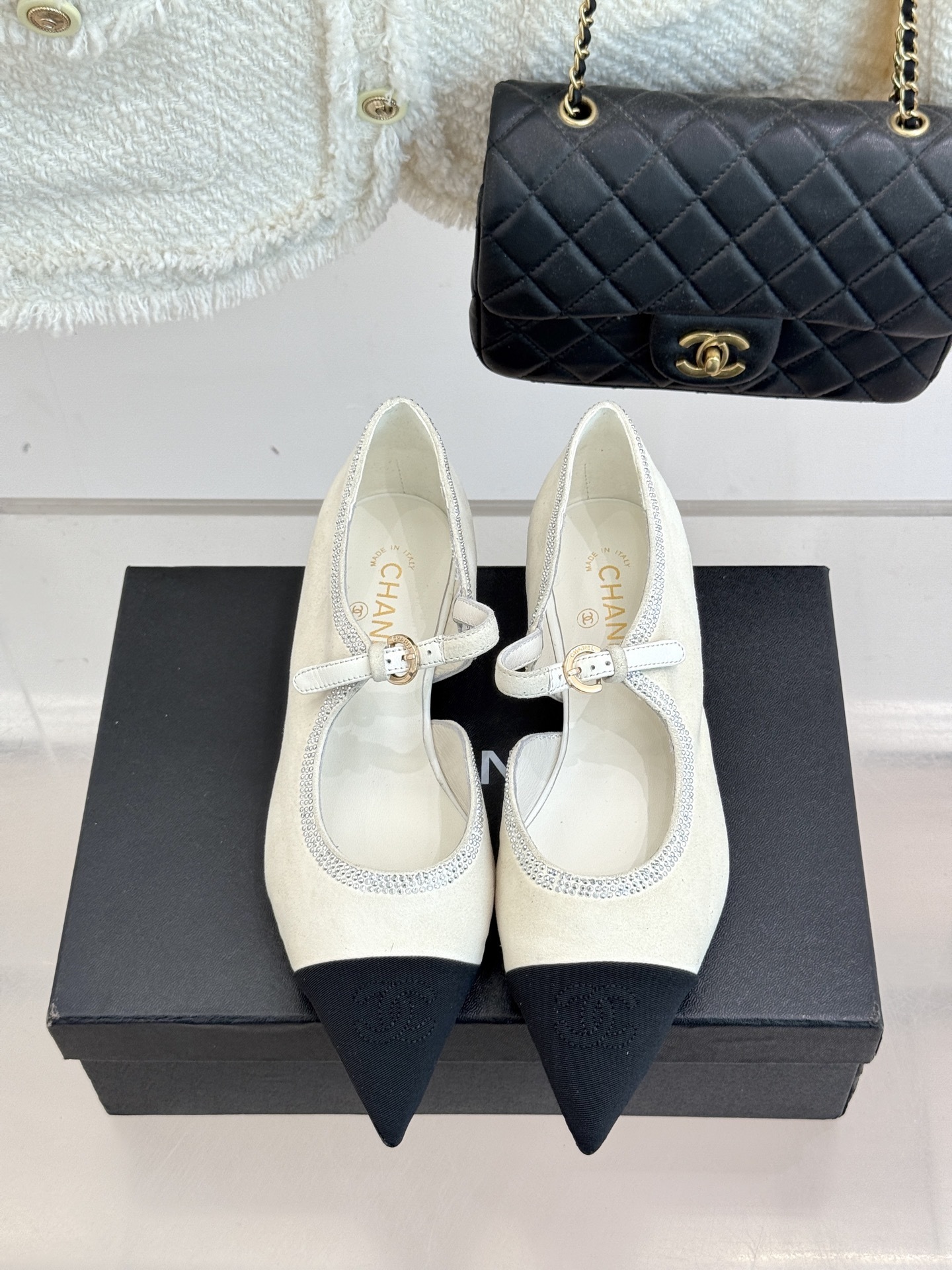 Luxury Chanel white suede Mary Jane flats with crystal trim and black cap toe displayed on a black designer box. - Hình 4