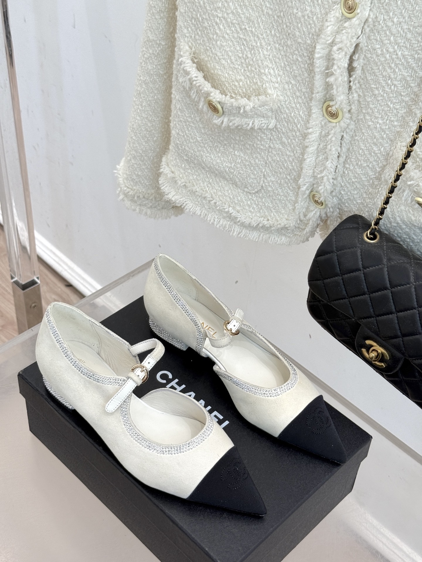 Luxury Chanel white suede Mary Jane flats with crystal trim and black cap toe displayed on a black designer box. - Hình 3