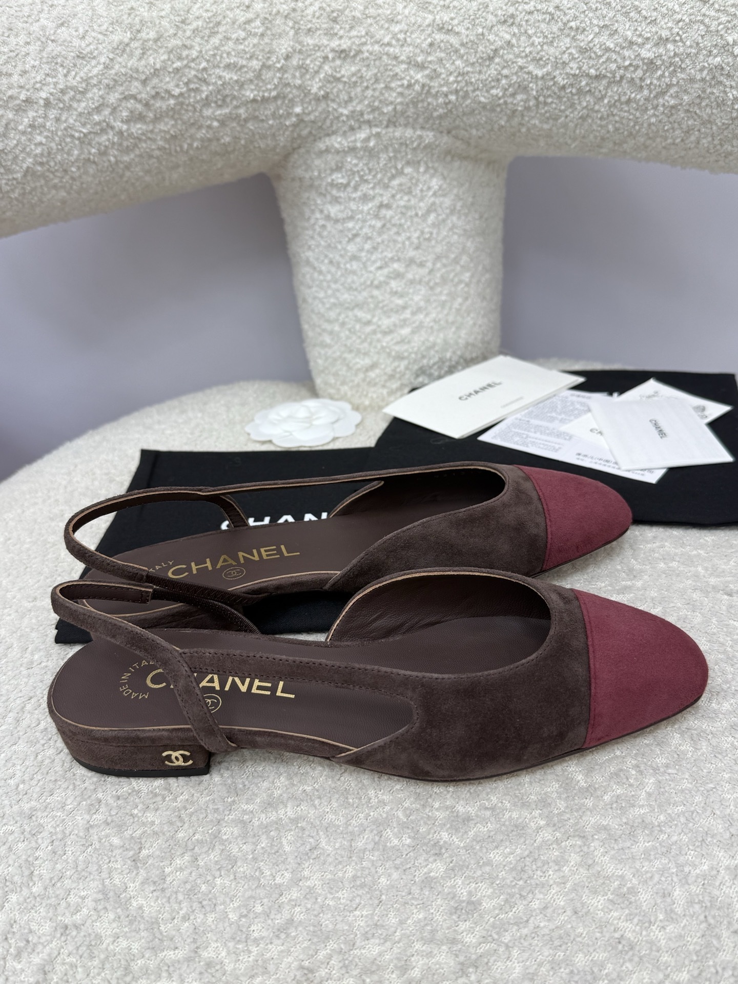 Pair of Chanel two-tone slingback flats in brown suede with burgundy cap toe on a white textured surface with packaging. - Hình 8
