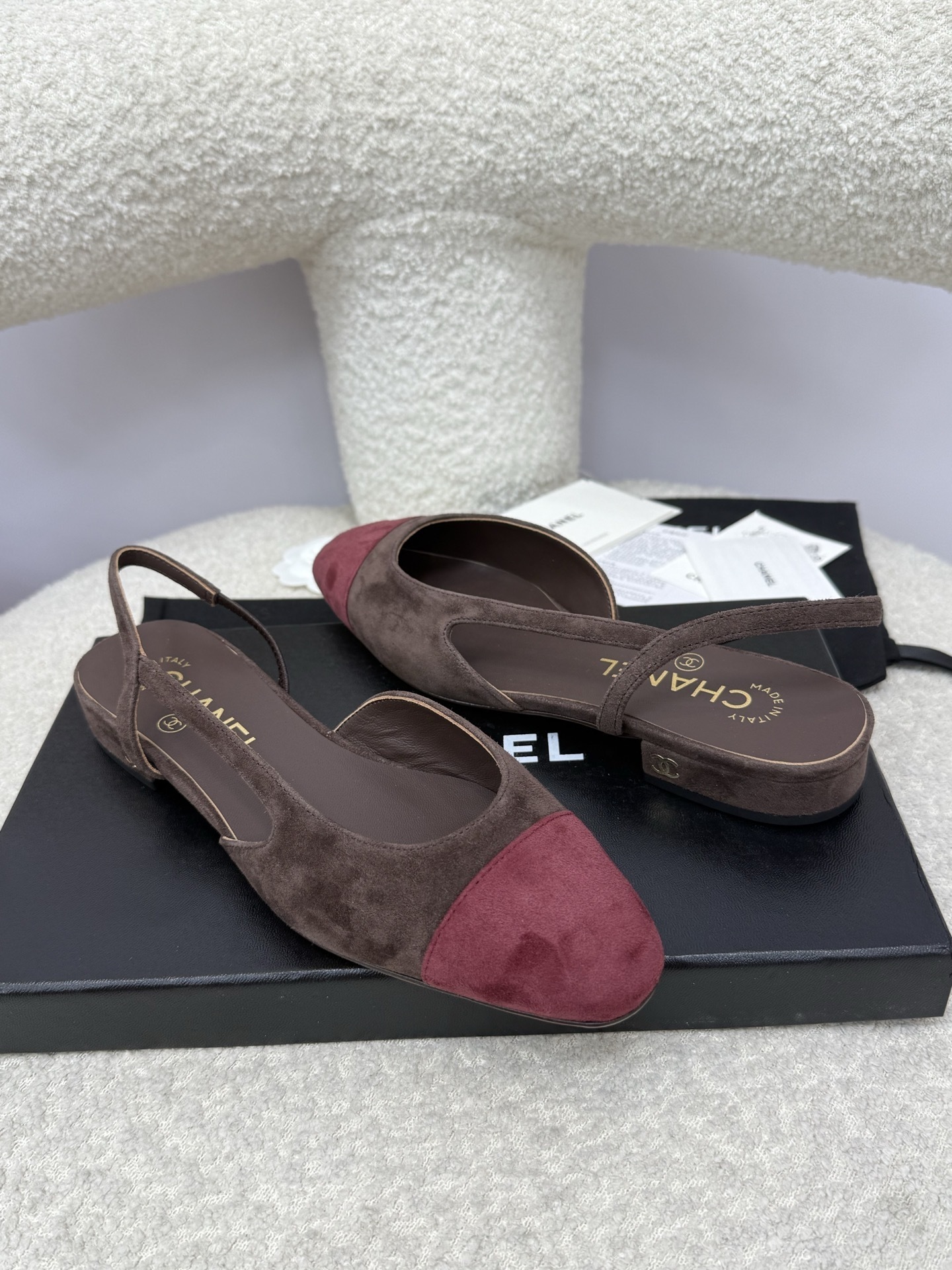 Pair of Chanel two-tone slingback flats in brown suede with burgundy cap toe on a white textured surface with packaging. - Hình 7