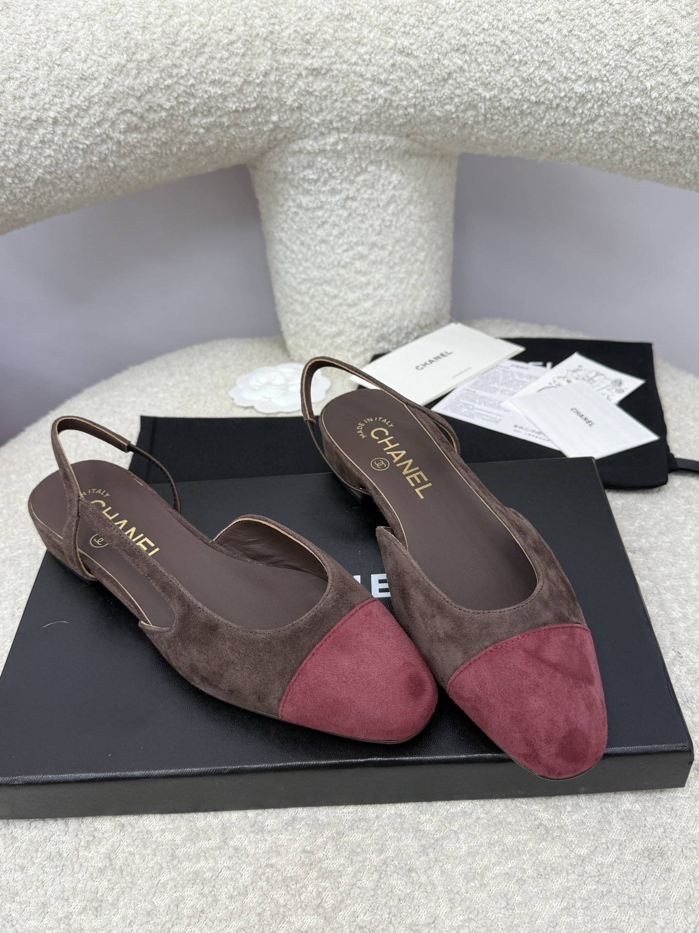 Pair of Chanel two-tone slingback flats in brown suede with burgundy cap toe on a white textured surface with packaging. - Hình 5