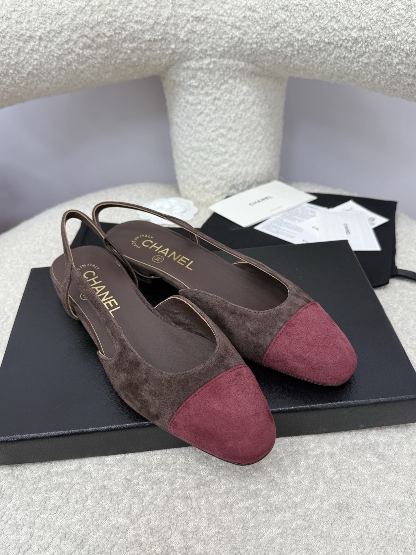 Pair of Chanel two-tone slingback flats in brown suede with burgundy cap toe on a white textured surface with packaging. - Hình 4
