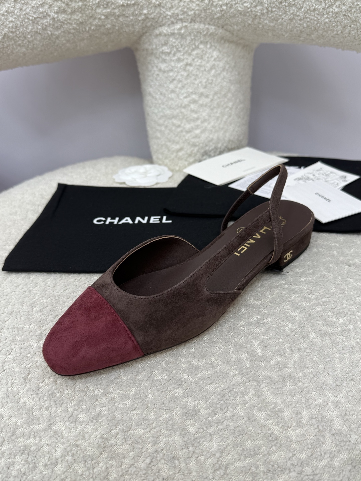 Pair of Chanel two-tone slingback flats in brown suede with burgundy cap toe on a white textured surface with packaging. - Hình 3