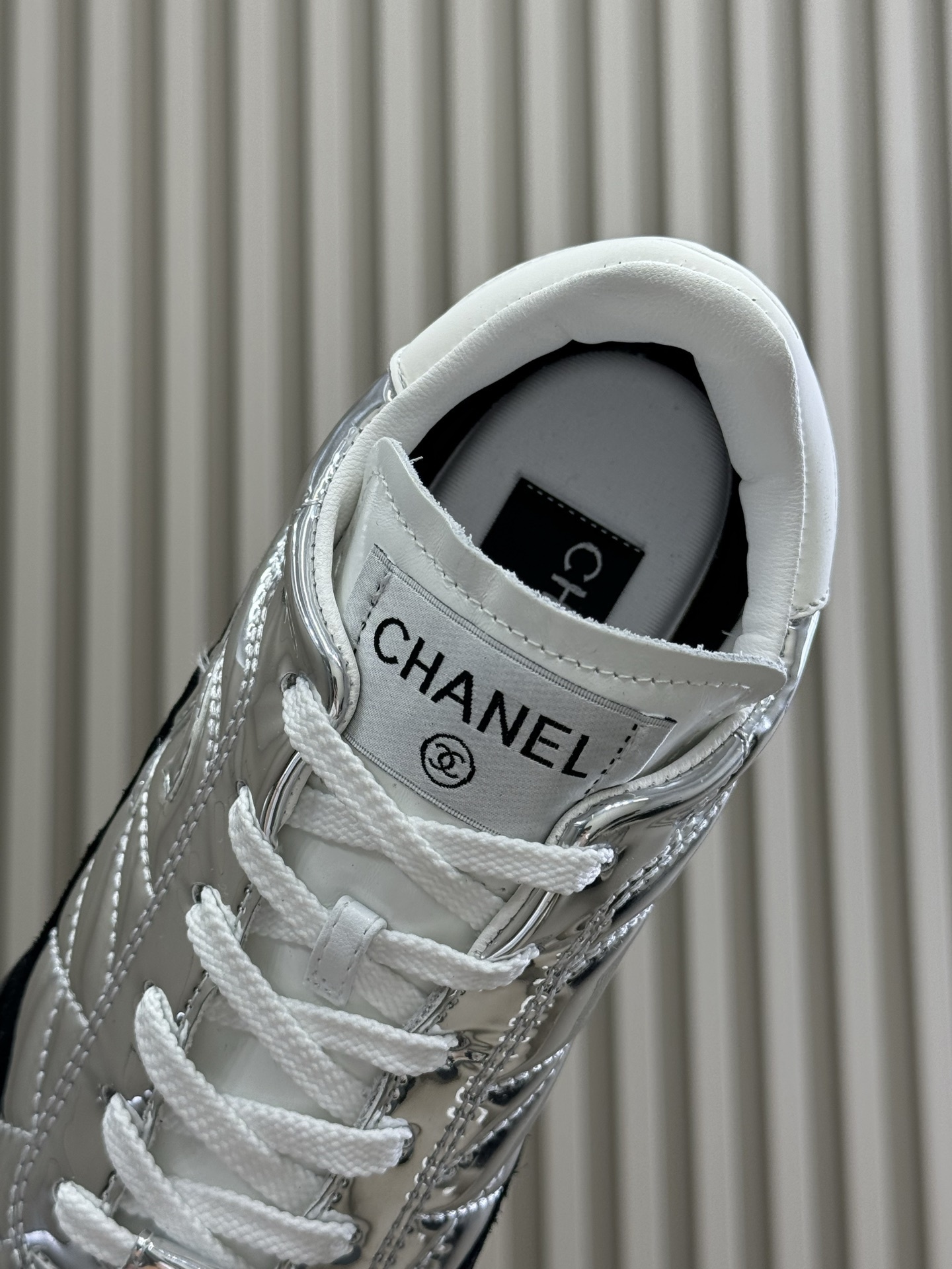 Chanel low-top sneakers with silver metallic quilted upper and black suede trim displayed on a black designer box. - Hình 8
