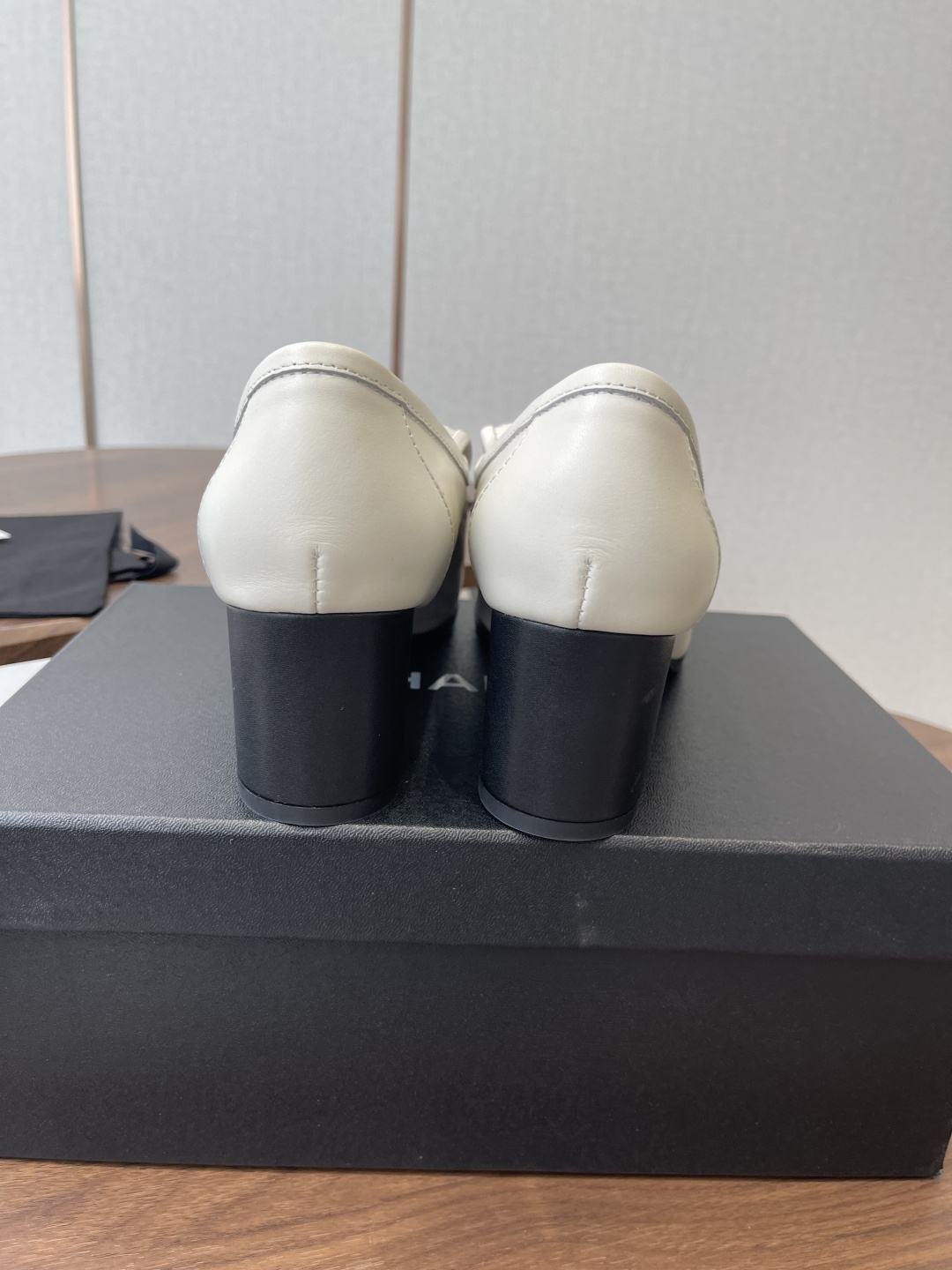 Chanel off-white quilted leather loafers with gold CC logo and black block heel on a wooden table - Hình 8