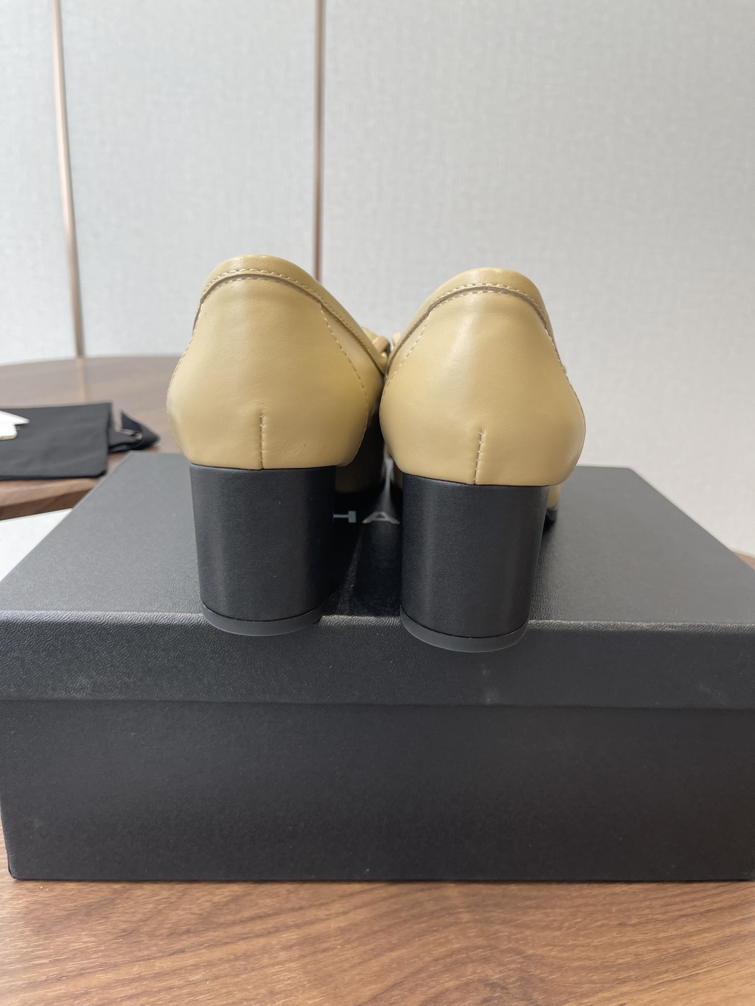 A pair of Chanel beige leather loafers with quilted gold CC logo displayed on a black shoe box. - Hình 8