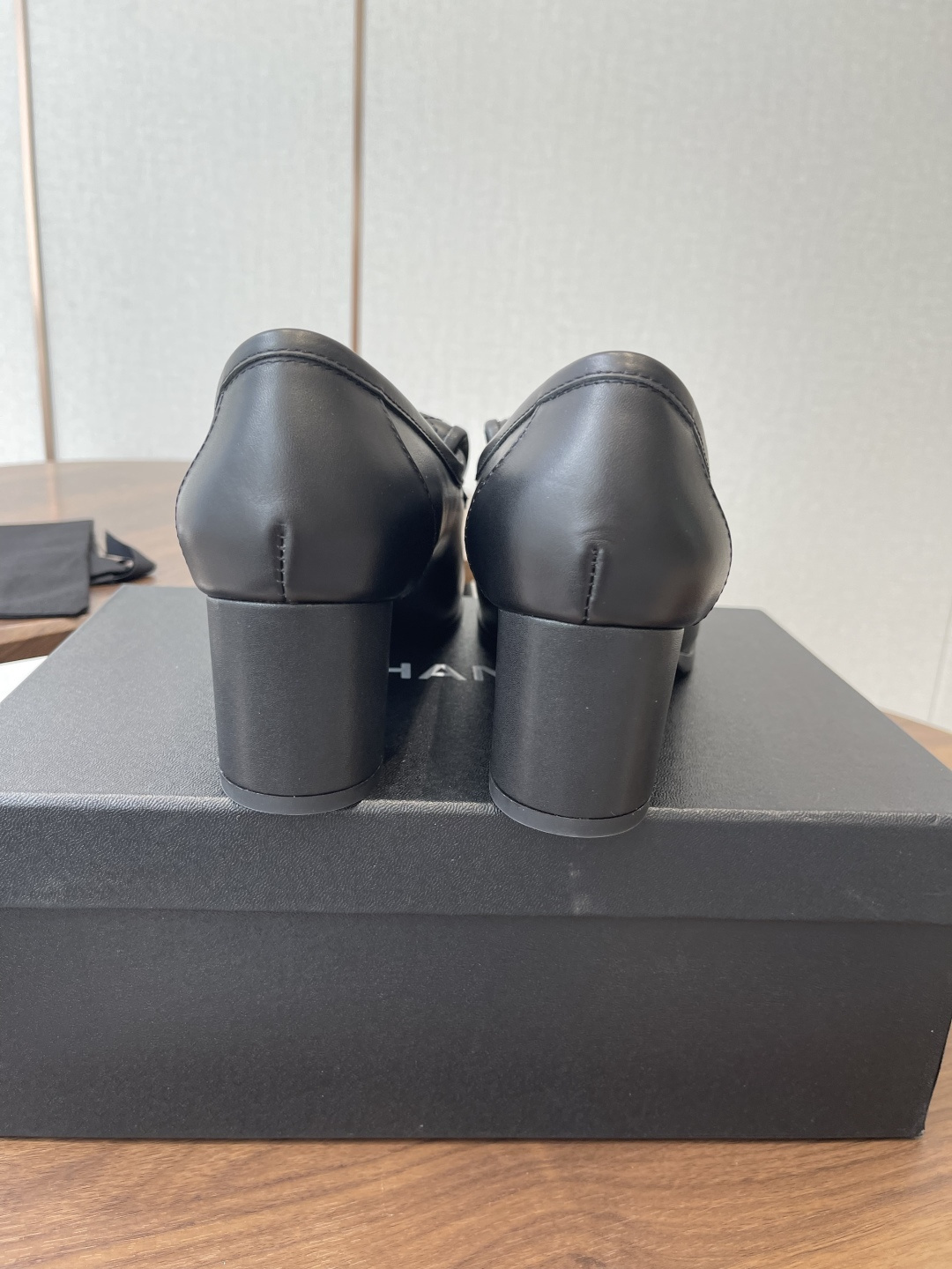 Elegant black leather loafers with quilted front flap and gold interlocking logo on a designer shoe box - Hình 8