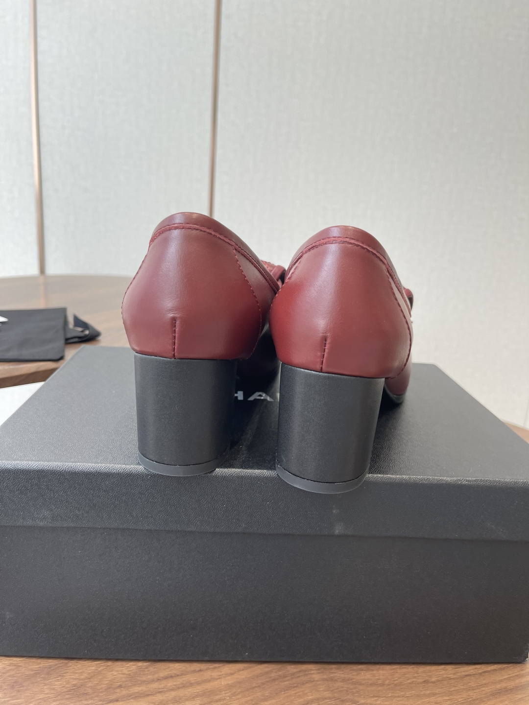 A pair of luxury burgundy Chanel quilted leather loafers with gold CC logos displayed on a black shoe box. - Hình 8