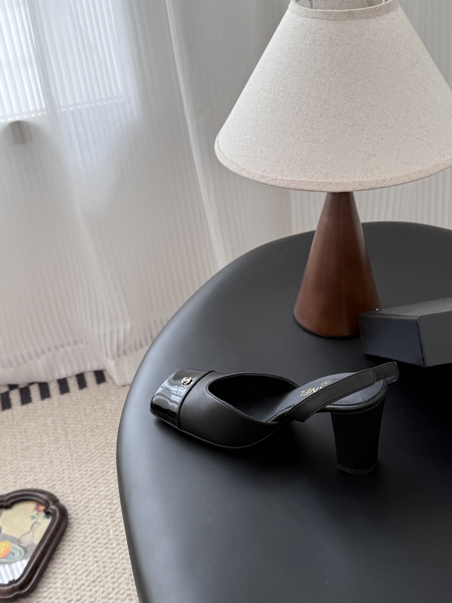 Pair of black Chanel leather slingback pumps with patent cap toe and gold CC logo displayed with a designer box. - Hình 8