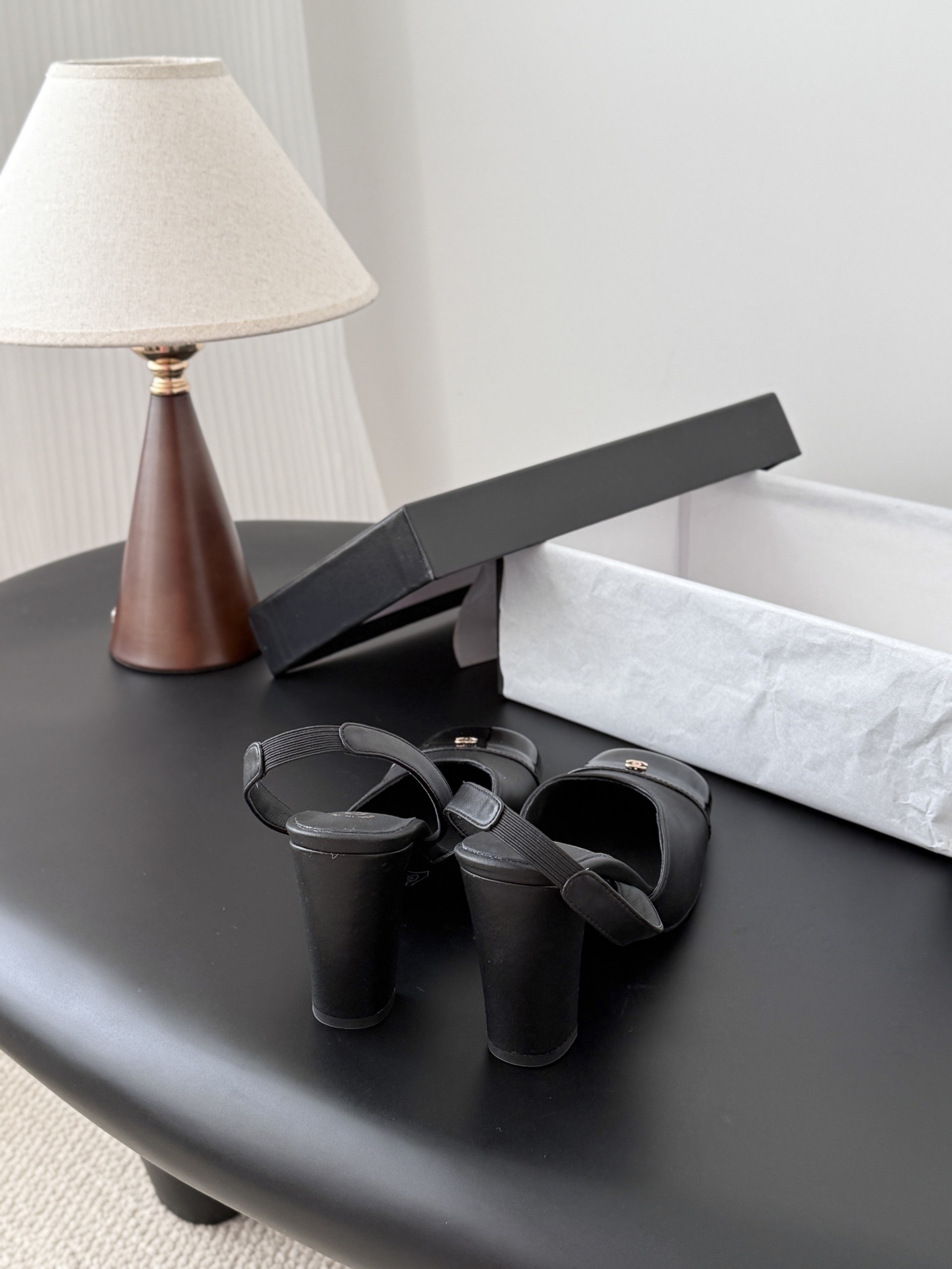 Pair of black Chanel leather slingback pumps with patent cap toe and gold CC logo displayed with a designer box. - Hình 3