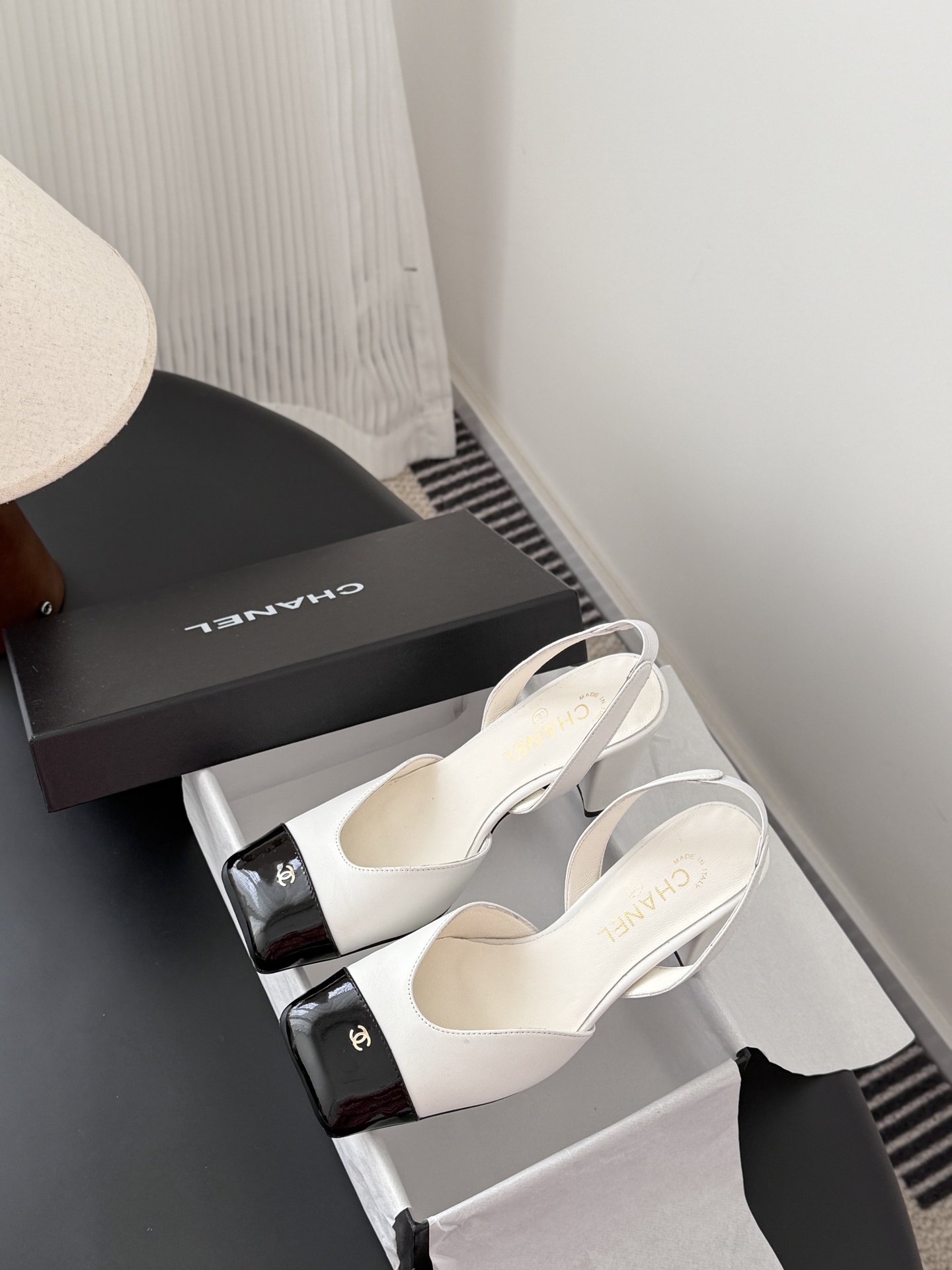 Luxury Chanel white leather slingback pumps with black patent cap toes and gold CC logo, displayed next to a Chanel shoe box. - Hình 9