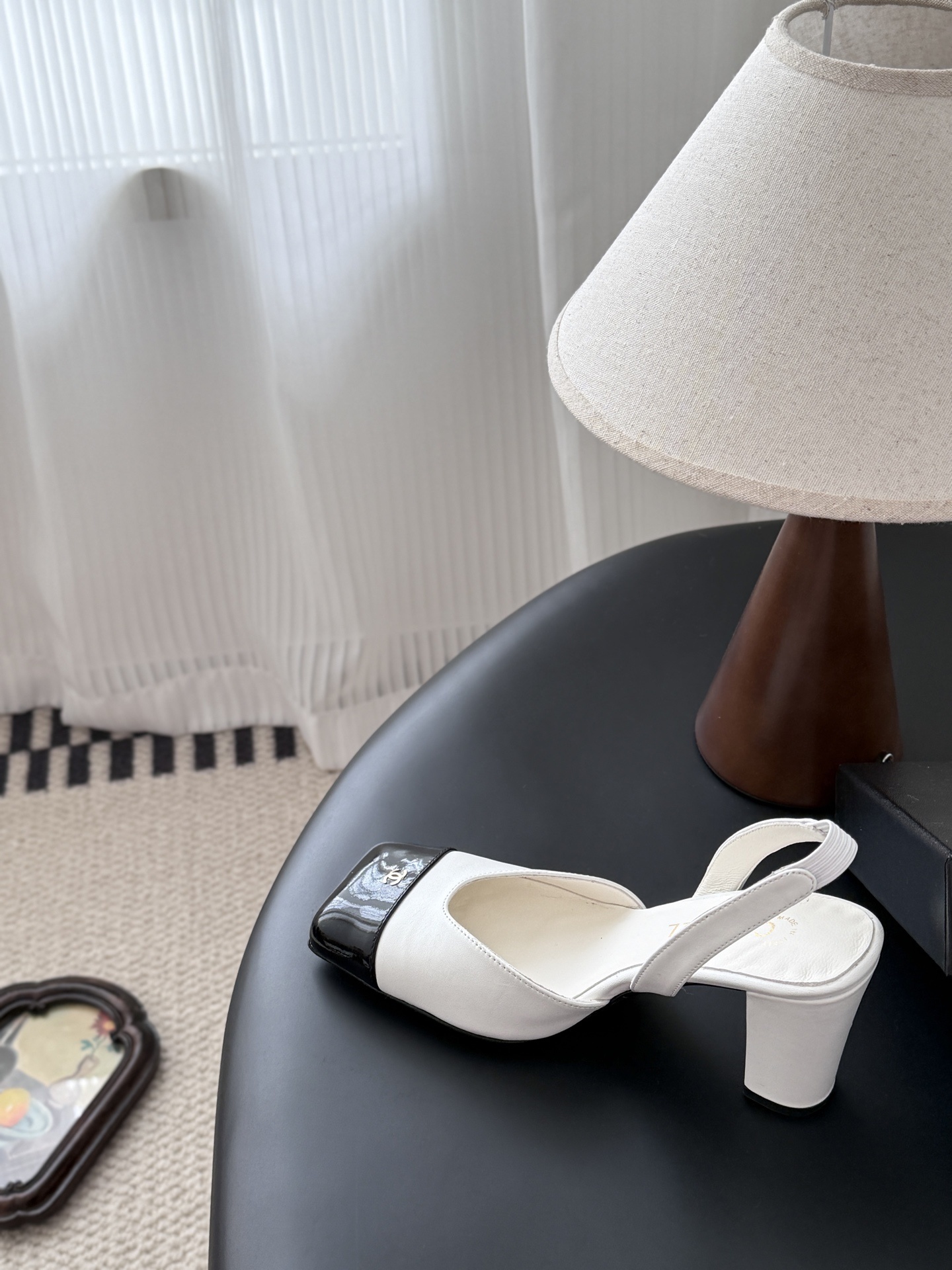 Luxury Chanel white leather slingback pumps with black patent cap toes and gold CC logo, displayed next to a Chanel shoe box. - Hình 8