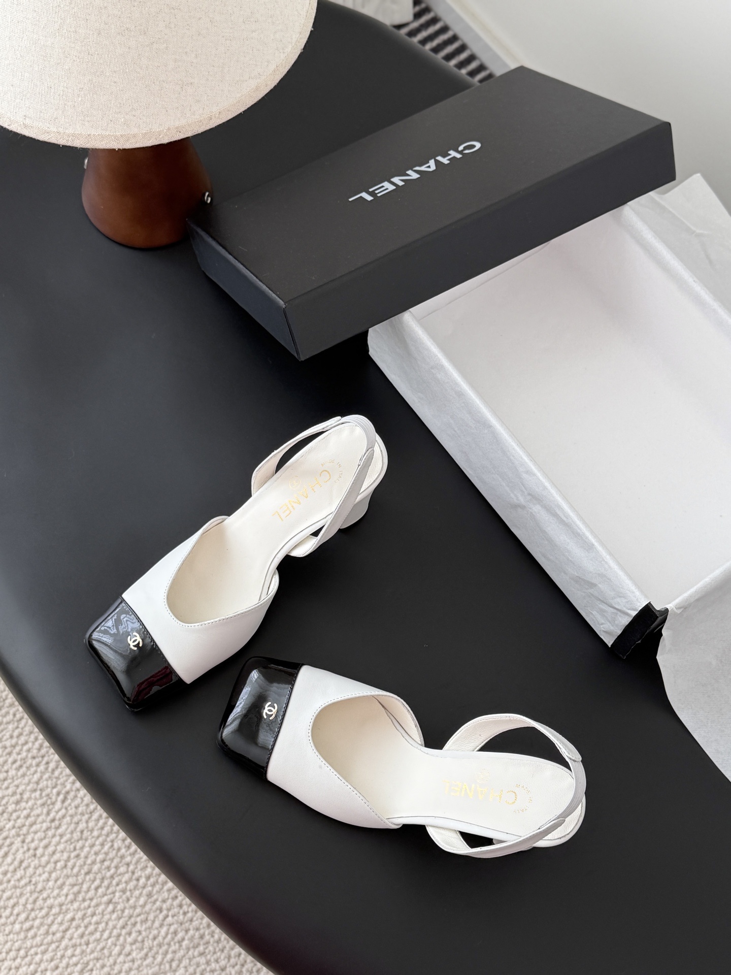 Luxury Chanel white leather slingback pumps with black patent cap toes and gold CC logo, displayed next to a Chanel shoe box. - Hình 6