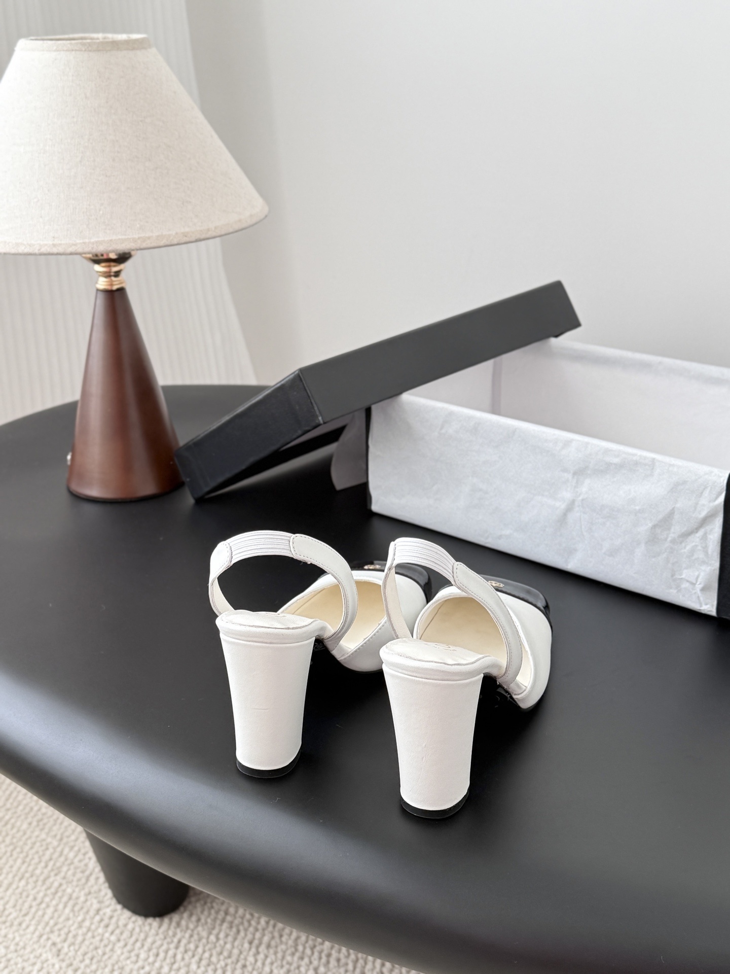 Luxury Chanel white leather slingback pumps with black patent cap toes and gold CC logo, displayed next to a Chanel shoe box. - Hình 3