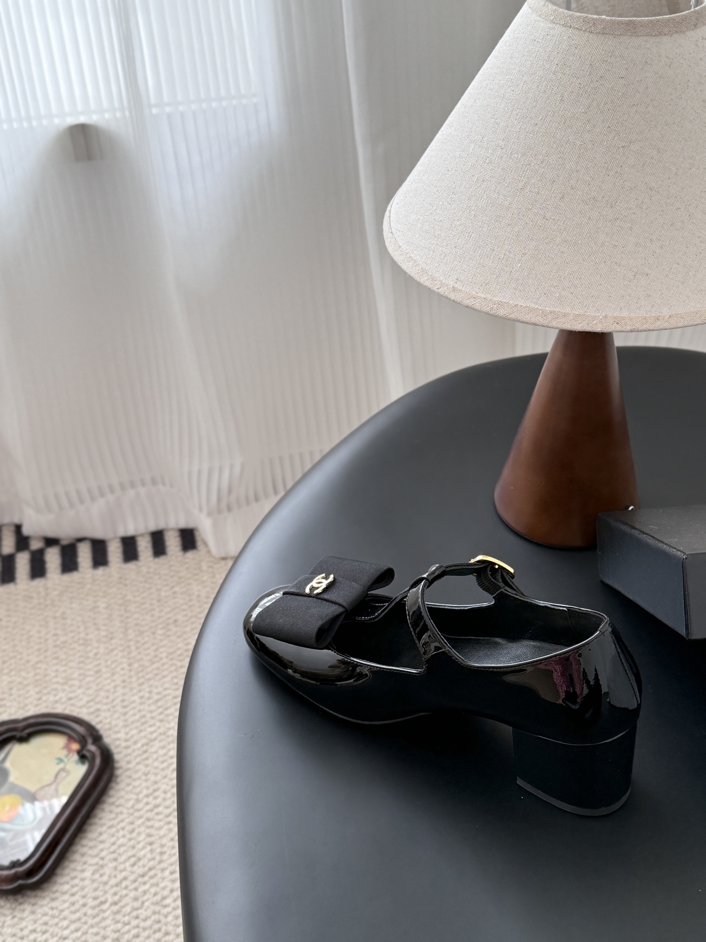 Pair of black Chanel patent leather Mary Jane pumps with T-strap, gold CC logo bow, and block heel next to a Chanel shoe box. - Hình 8