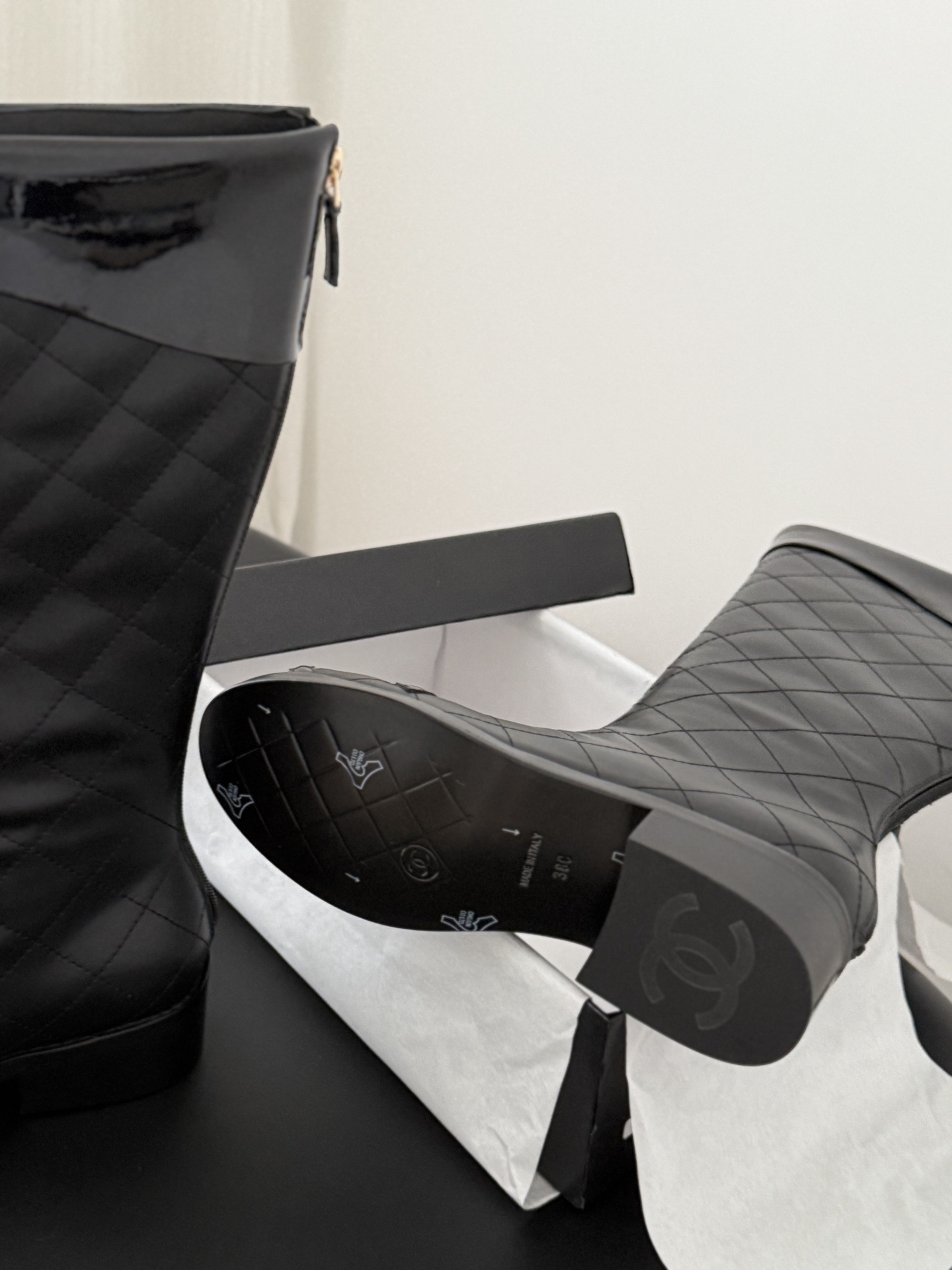 Pair of black Chanel quilted leather knee-high boots with CC logo on the toe and patent leather trim. - Hình 5