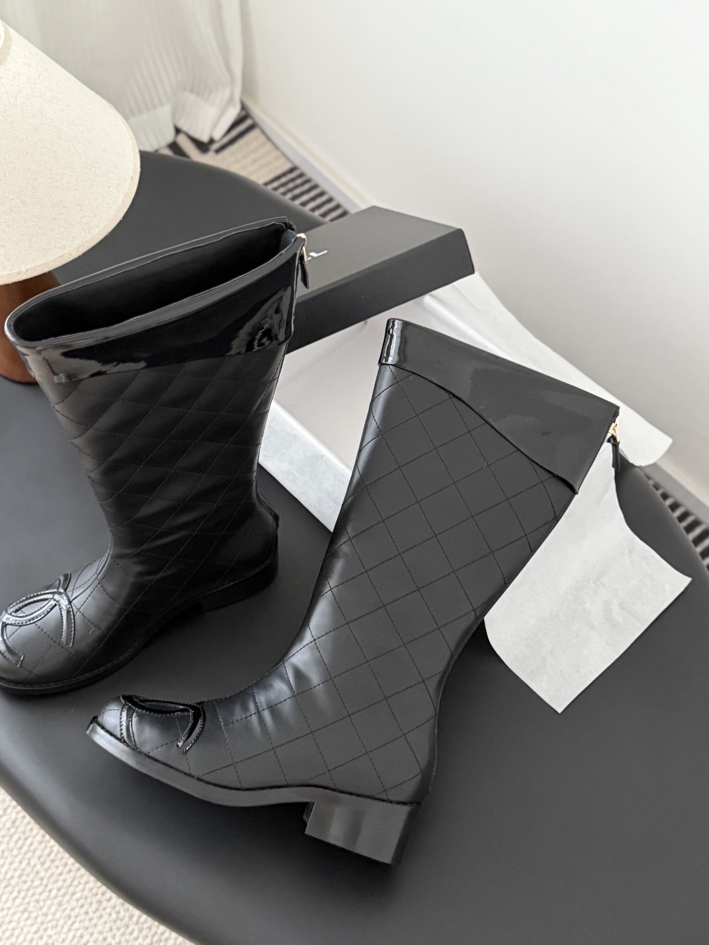 Pair of black Chanel quilted leather knee-high boots with CC logo on the toe and patent leather trim. - Hình 4