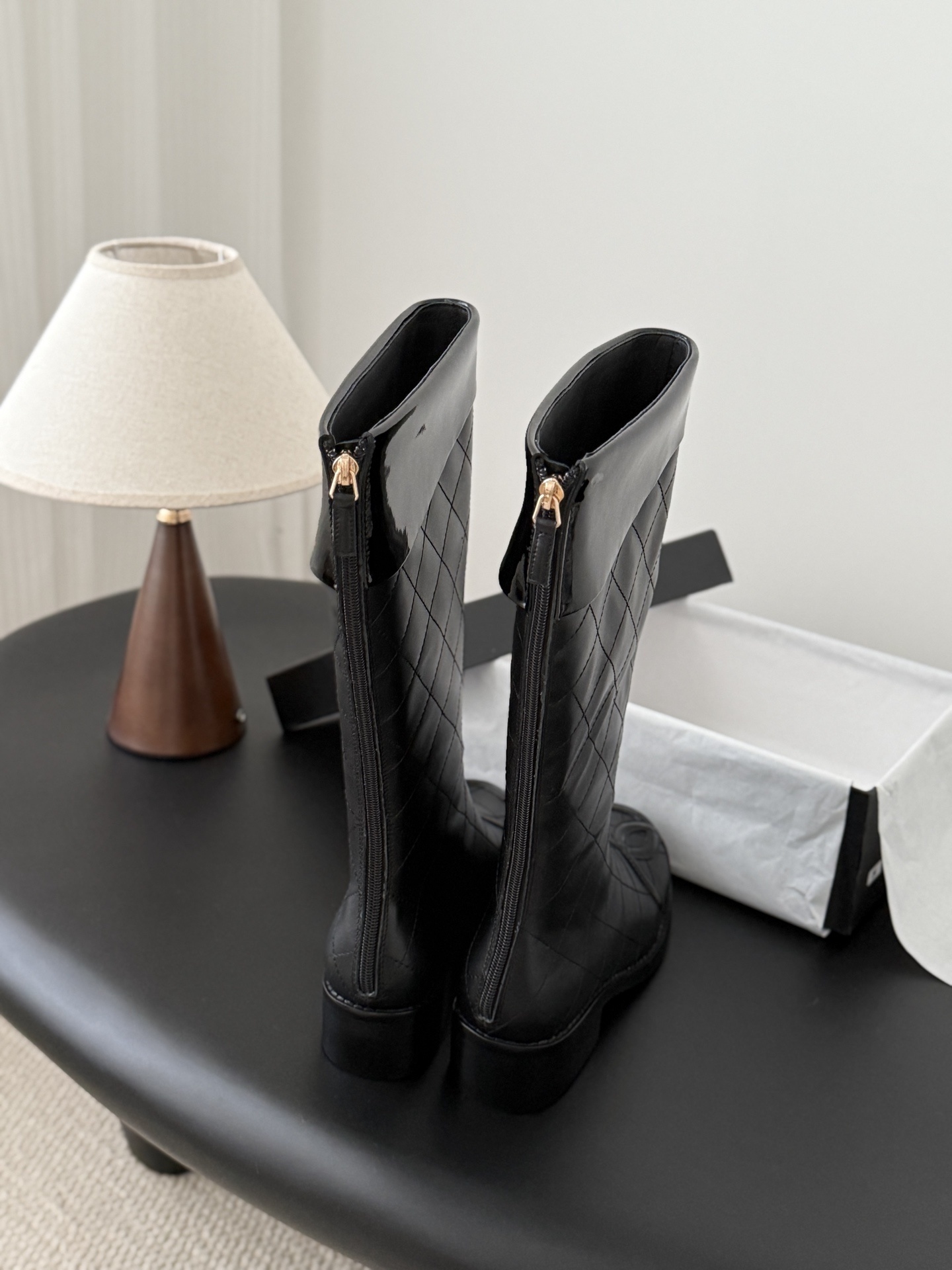 Pair of black Chanel quilted leather knee-high boots with CC logo on the toe and patent leather trim. - Hình 3