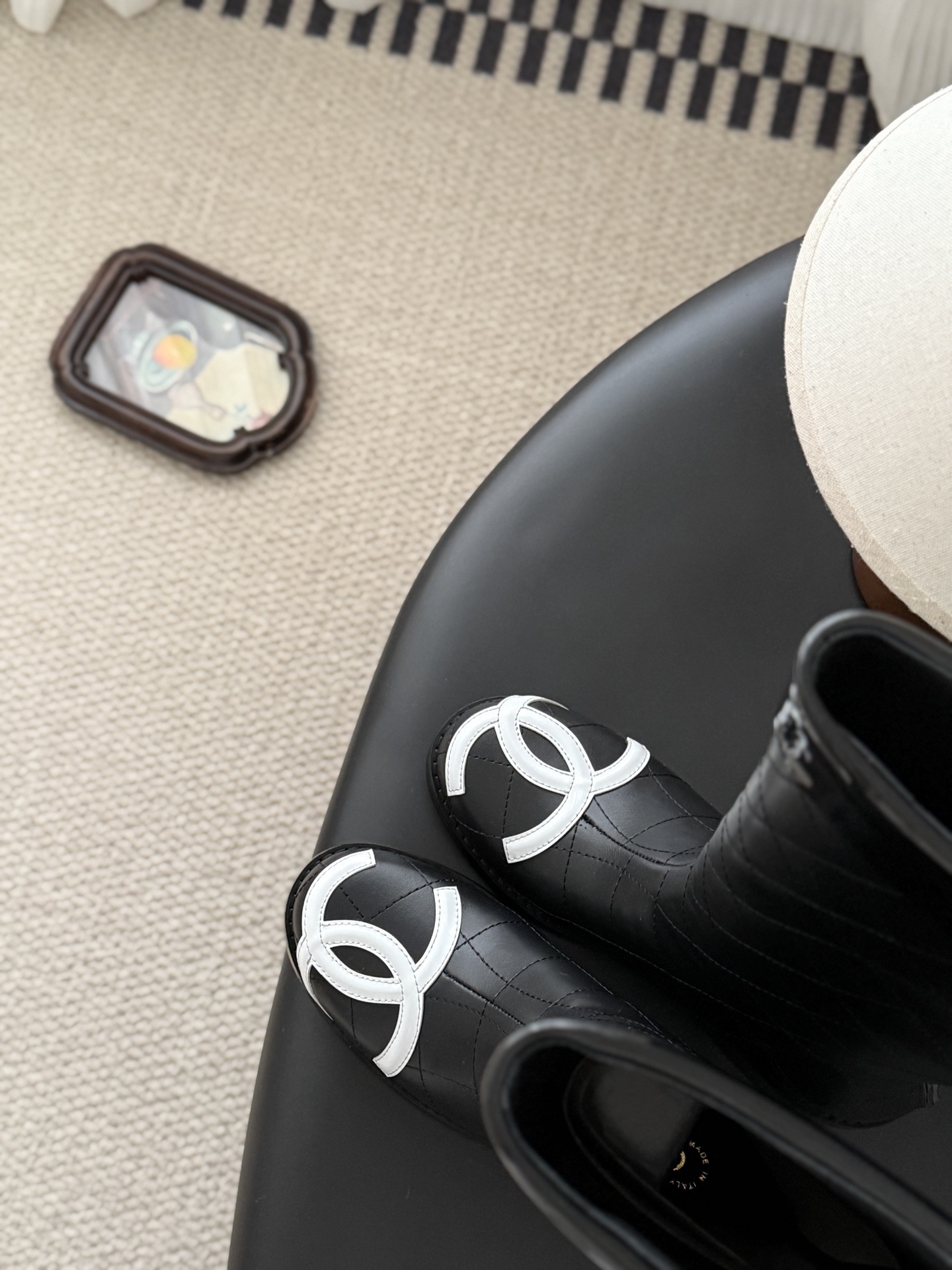 A pair of Chanel black quilted leather knee-high boots with white interlocking CC logos on the toe caps and gold-tone back zippers. - Hình 7