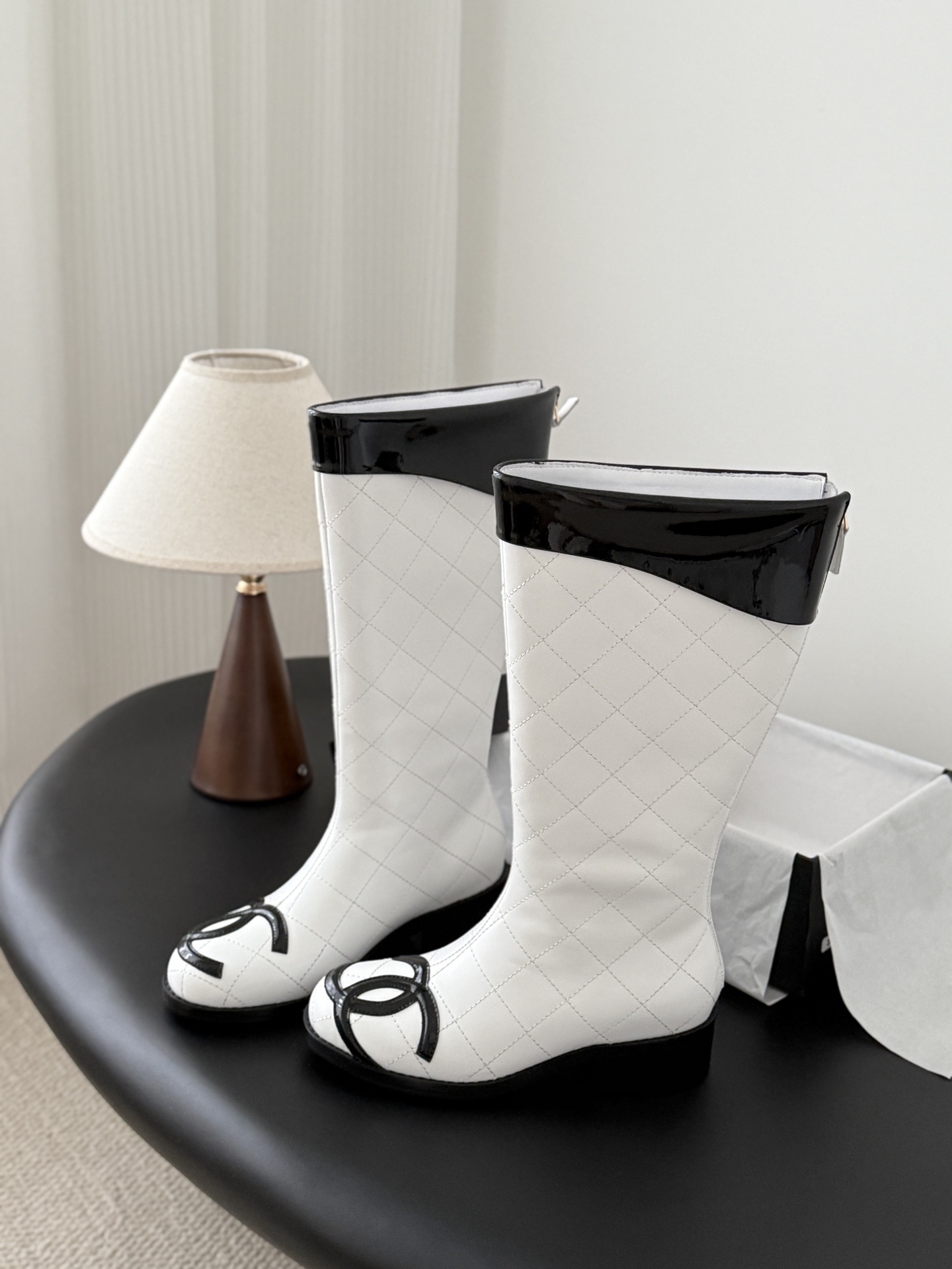 Pair of luxury white quilted leather knee-high boots with black patent trim and iconic logo on the toe. - Hình 6