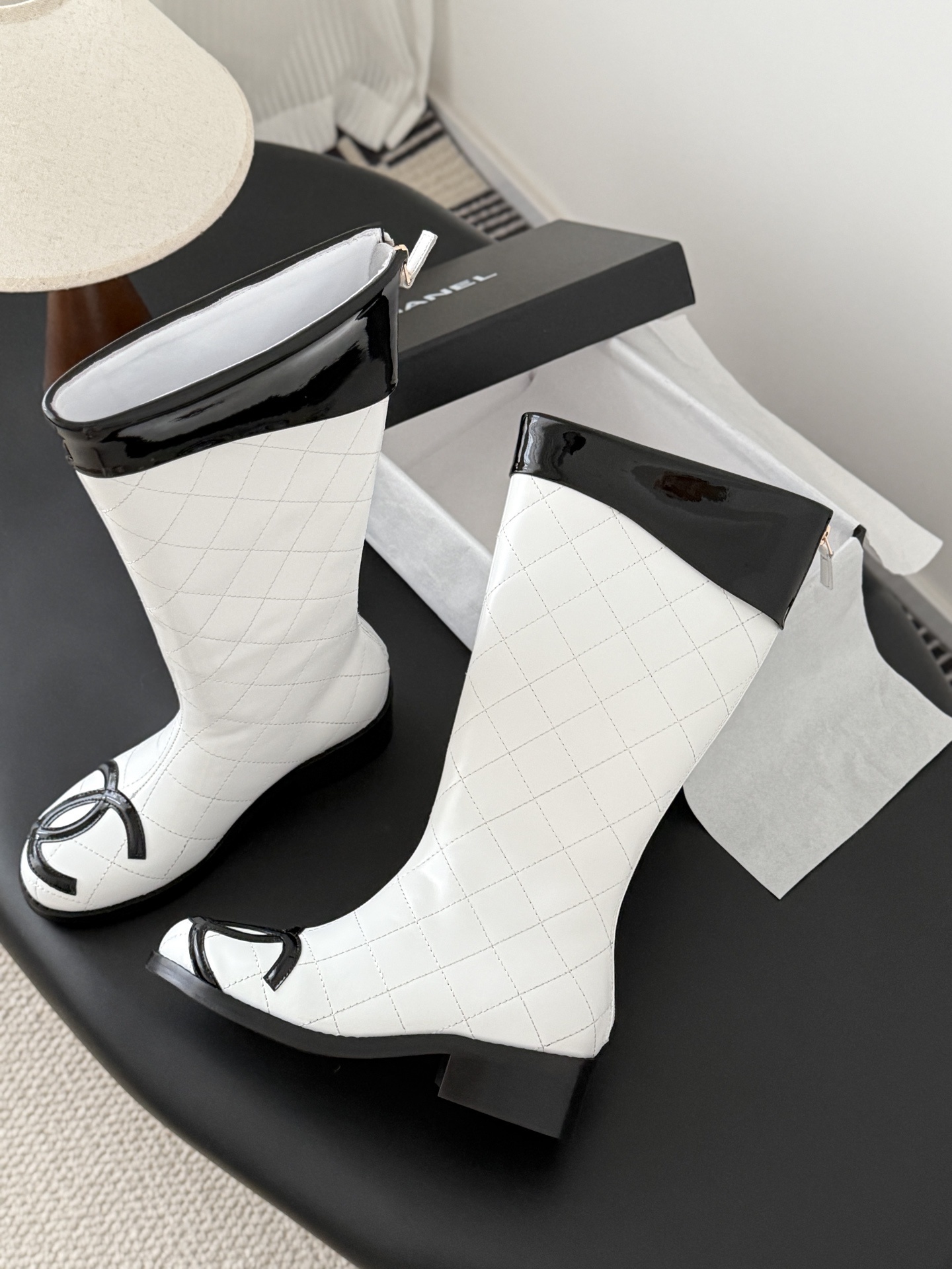 Pair of luxury white quilted leather knee-high boots with black patent trim and iconic logo on the toe. - Hình 4