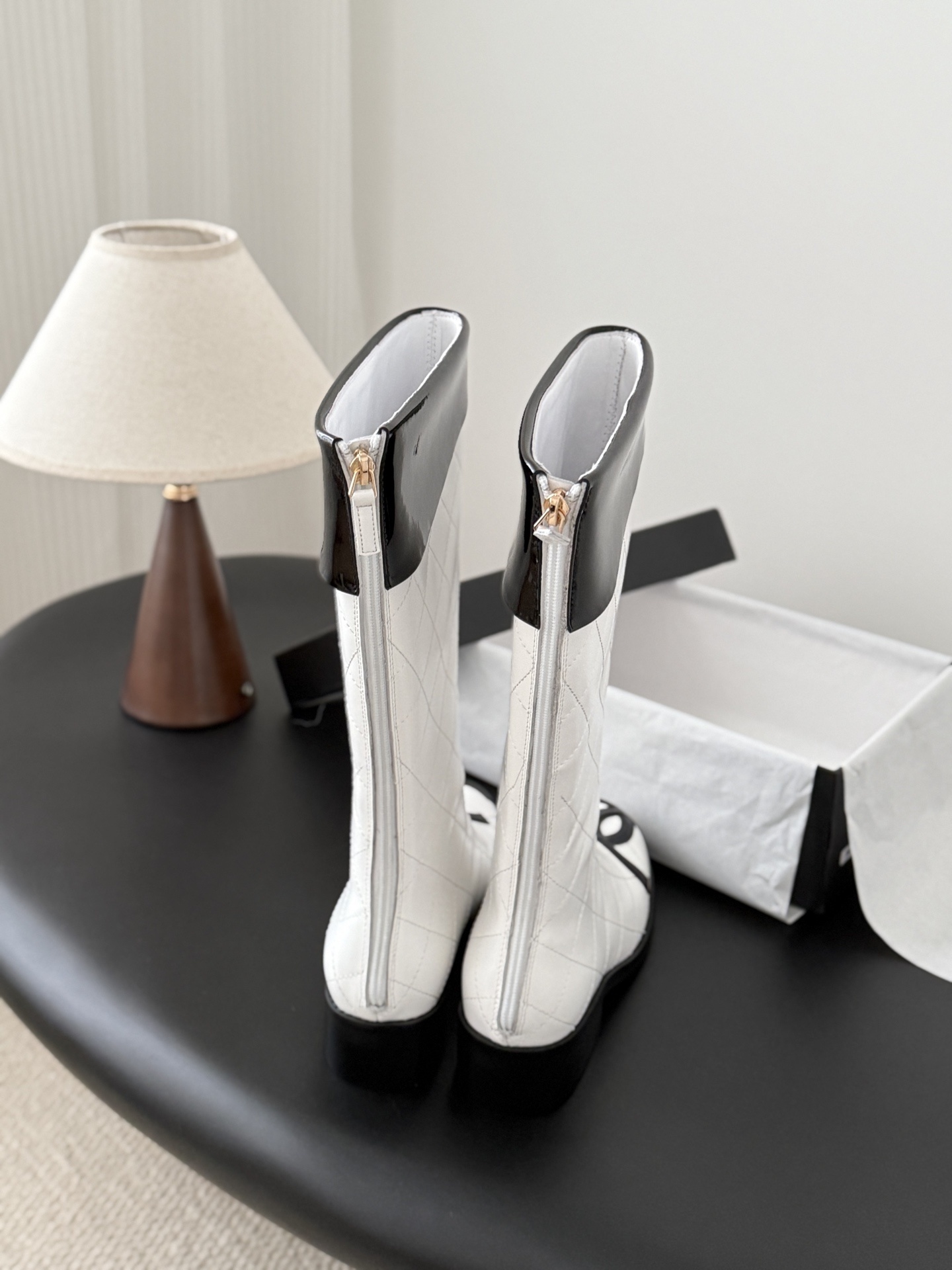 Pair of luxury white quilted leather knee-high boots with black patent trim and iconic logo on the toe. - Hình 3