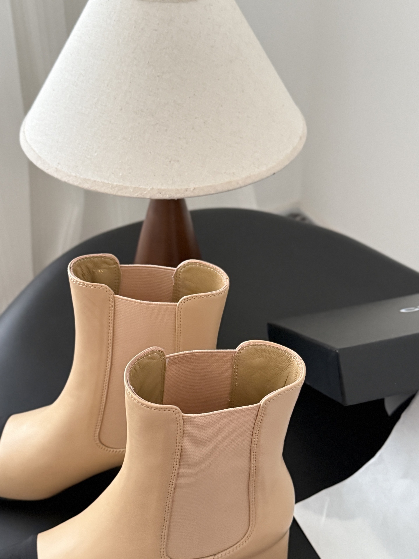 Chanel beige leather ankle boots with black toe caps and block heels displayed next to a black Chanel shoe box. - Hình 7
