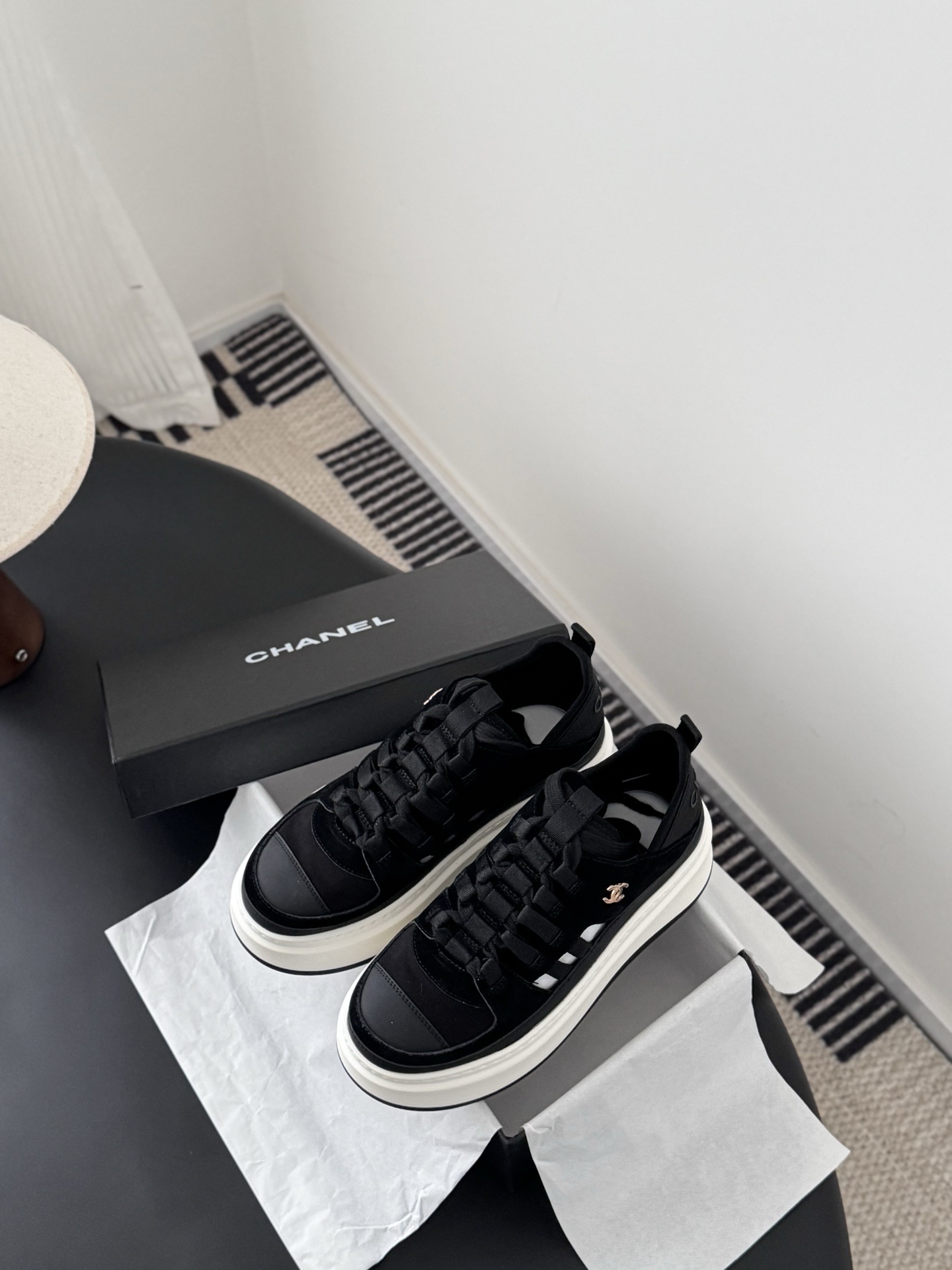 A pair of Chanel black suede and fabric sneakers with chunky white platform soles and gold CC logo next to a branded Chanel box. - Hình 6